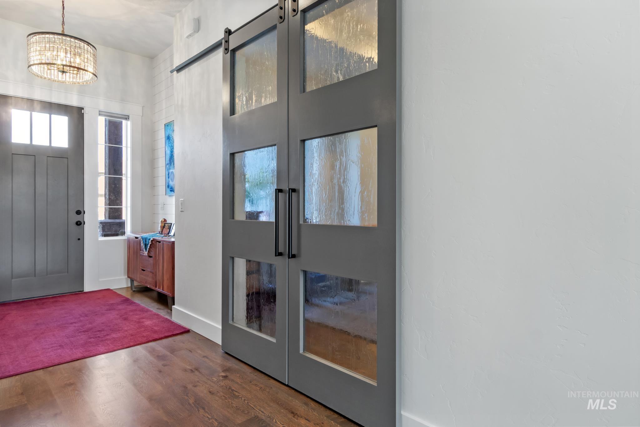 Foyer entrance with a barn door, dark wood-type flooring, french doors, and a chandelier