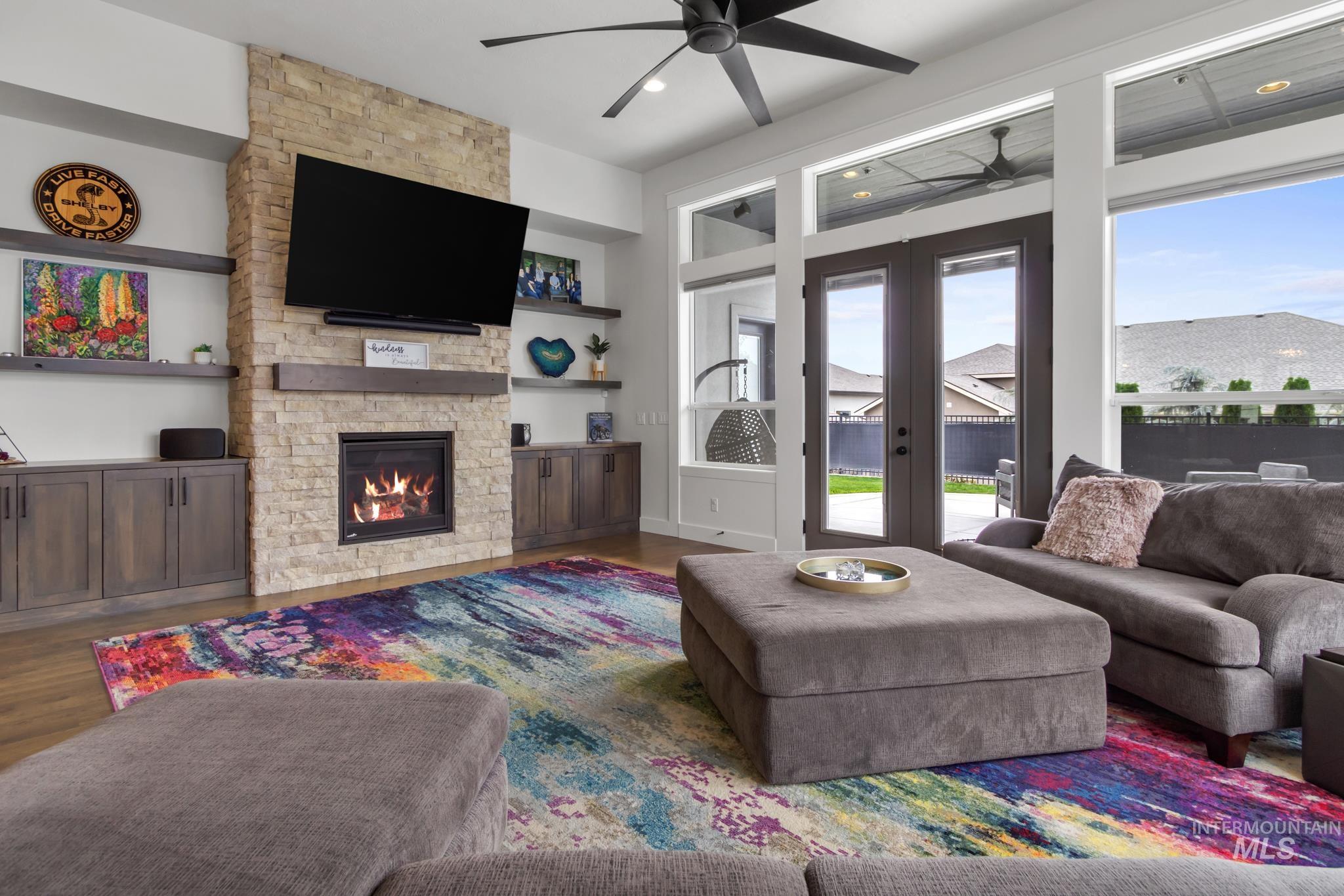 Living room with french doors, ceiling fan, wood finished floors, a fireplace, and built in shelves