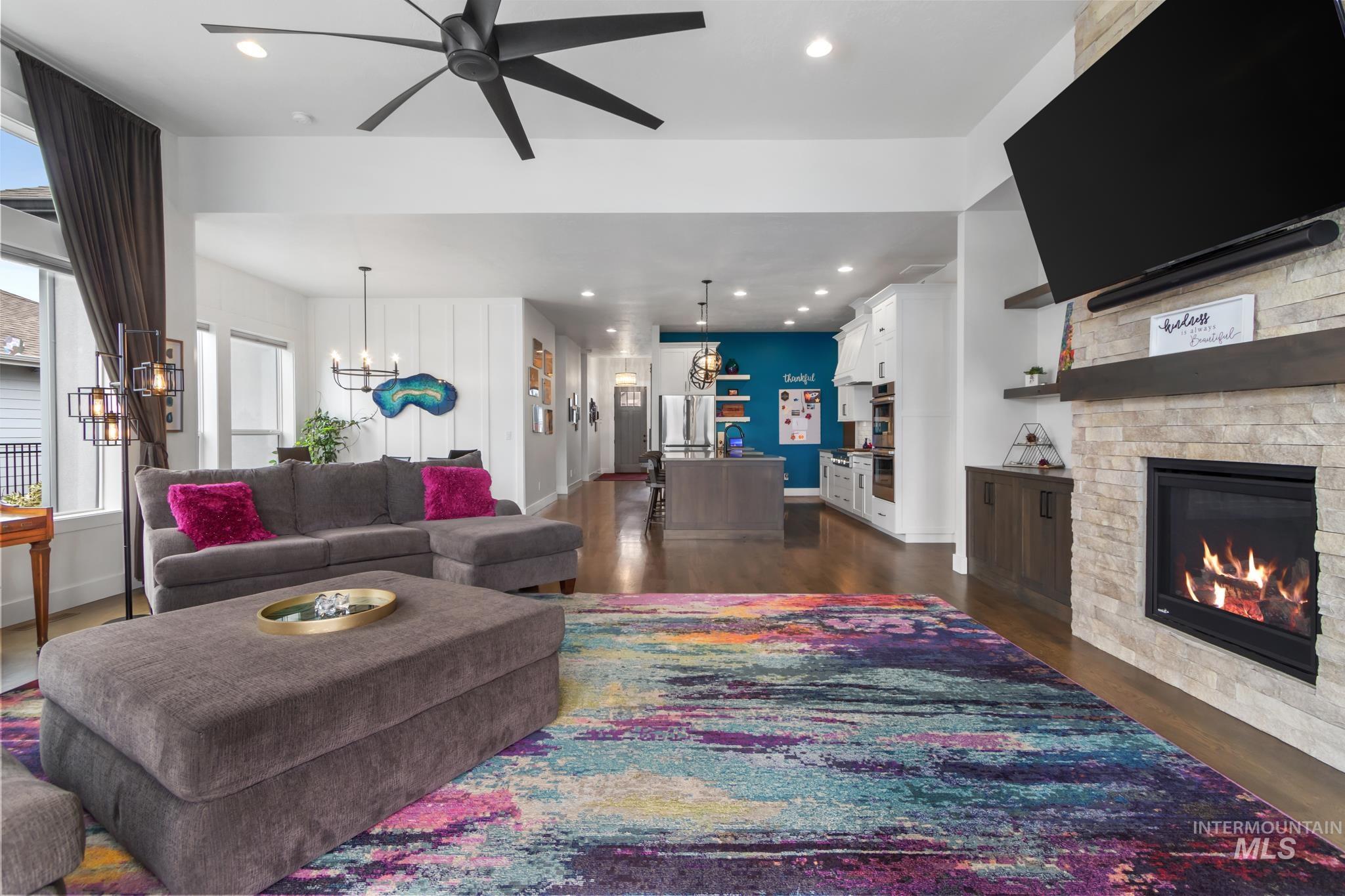 Living area featuring recessed lighting, dark wood-style flooring, a fireplace, ceiling fan, and a chandelier