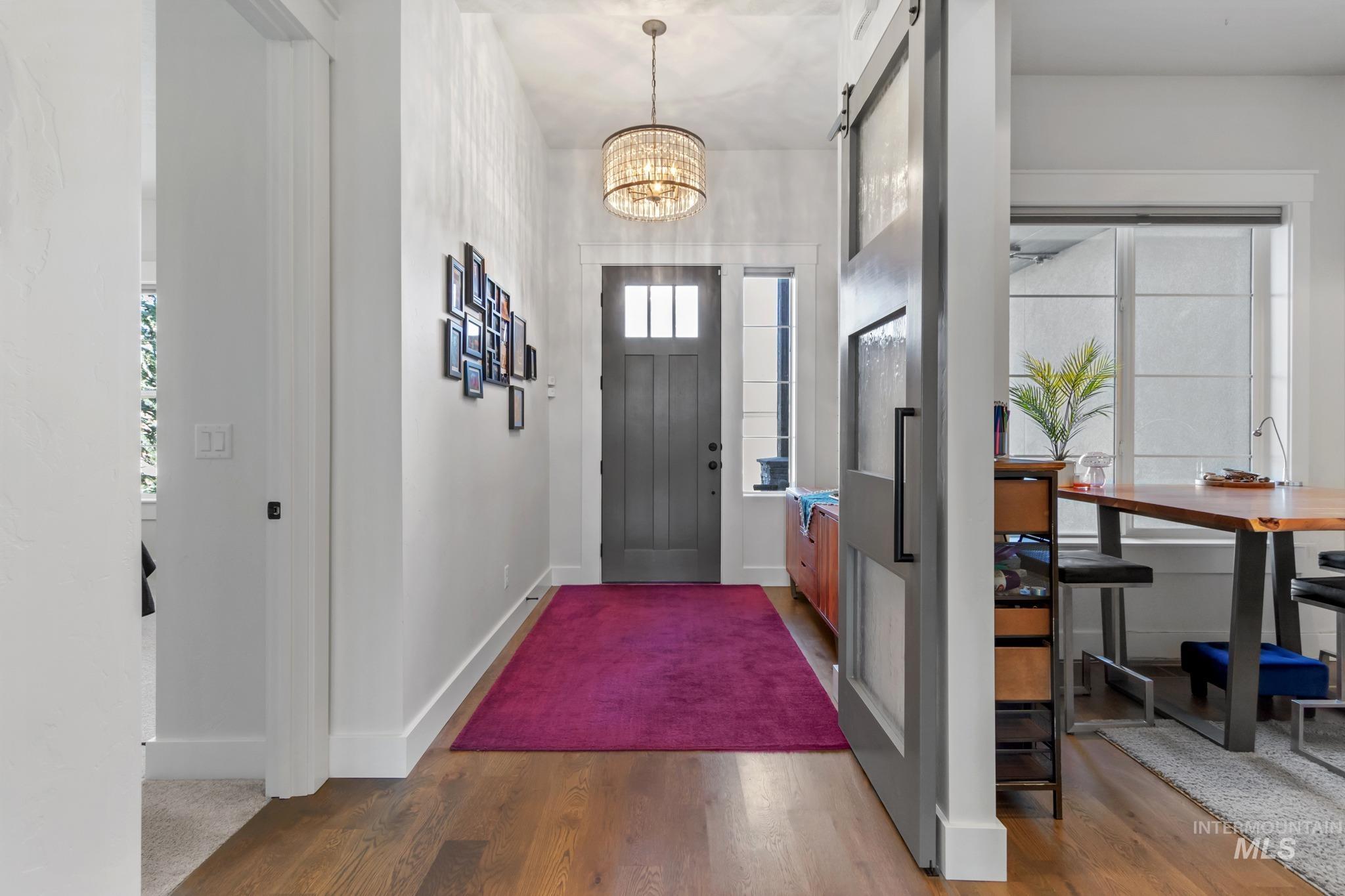 Foyer featuring wood finished floors, a barn door, and a chandelier