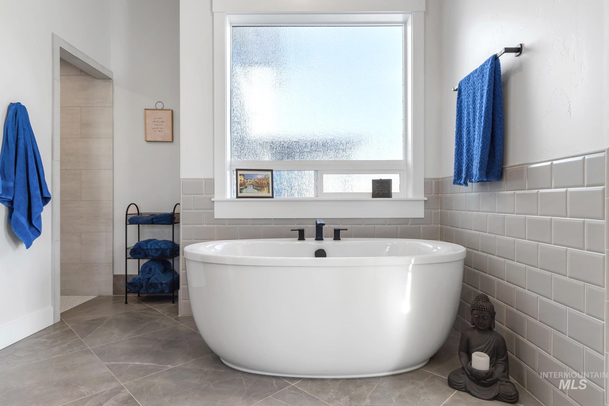 Full bathroom featuring a soaking tub, tile walls, and tile patterned floors