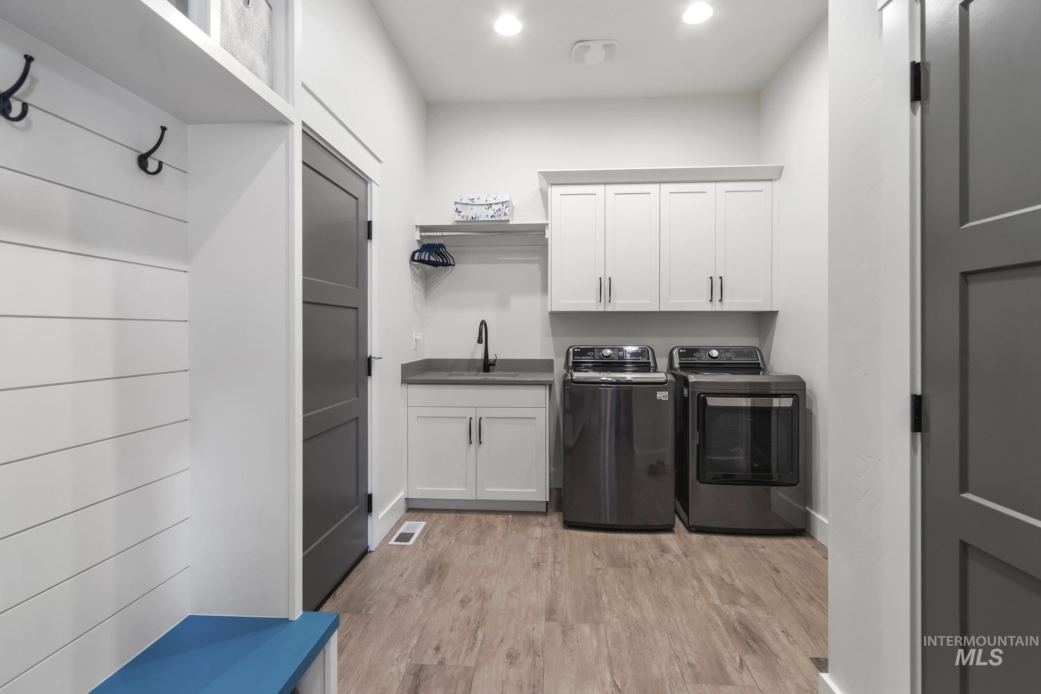 Laundry area with light wood-type flooring, washer and clothes dryer, cabinet space, and recessed lighting