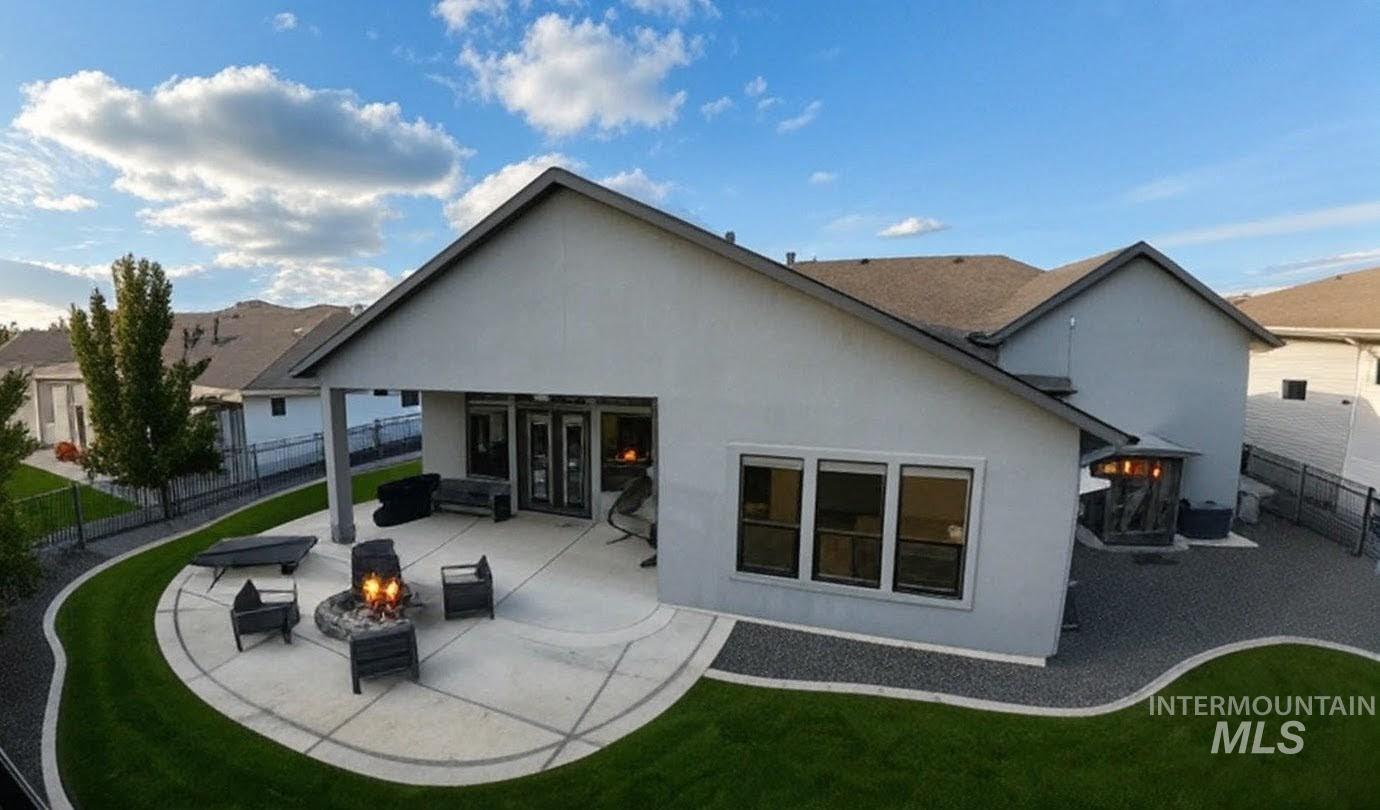 Rear view of property with an outdoor fire pit, a patio area, stucco siding, and a fenced backyard