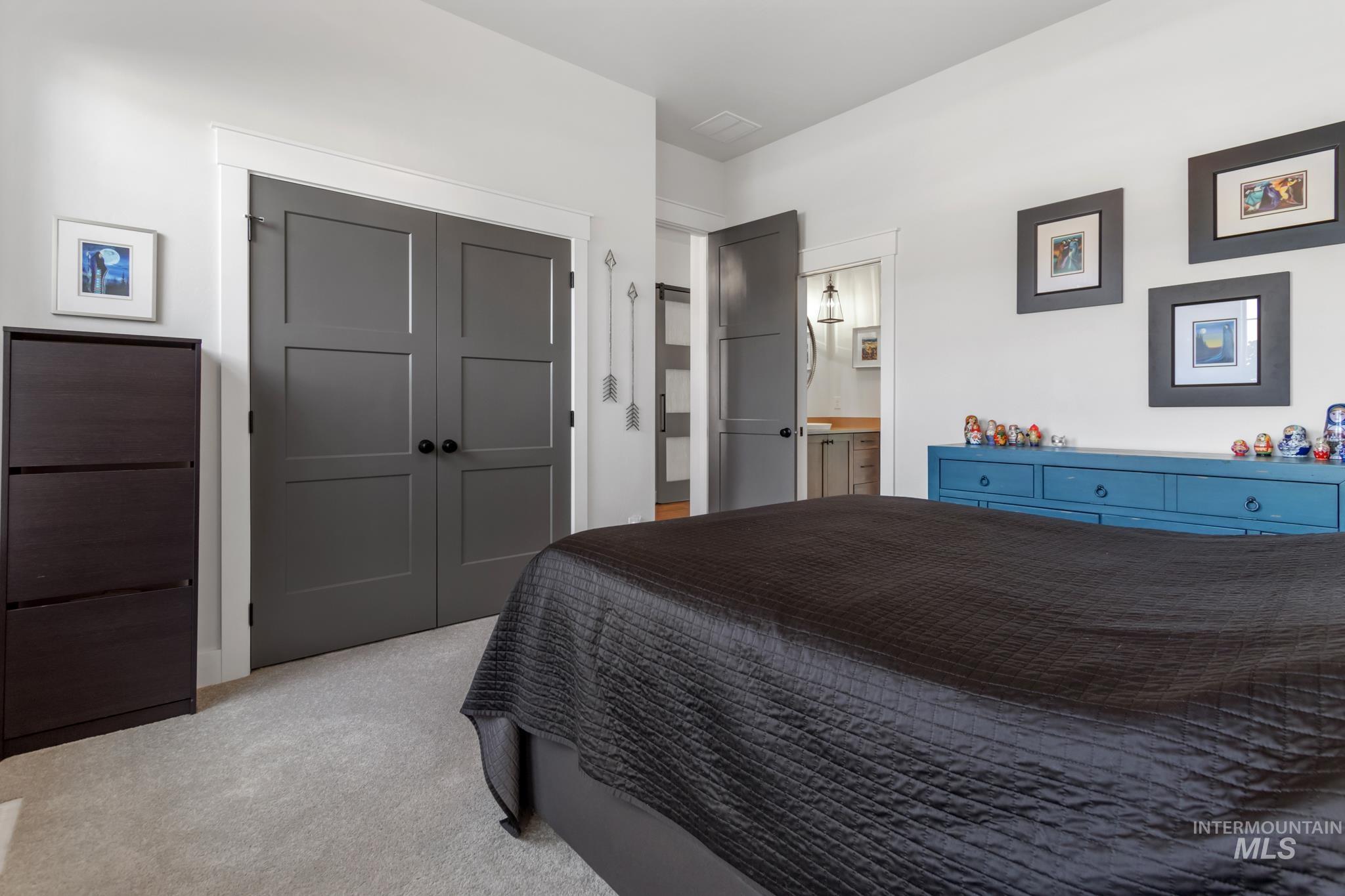 Carpeted bedroom featuring a closet and ensuite bath