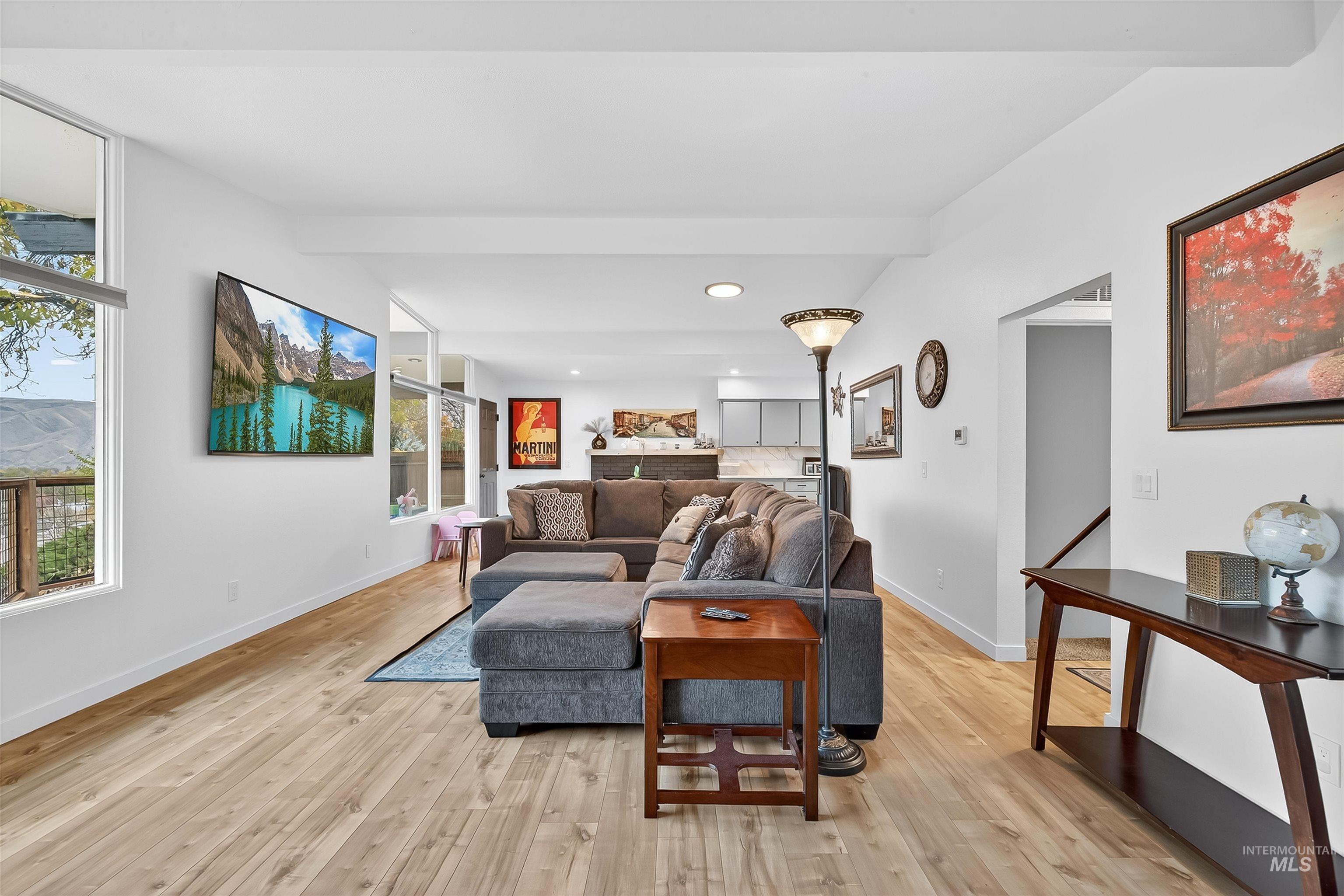 Living area with light wood finished floors, beam ceiling, and recessed lighting