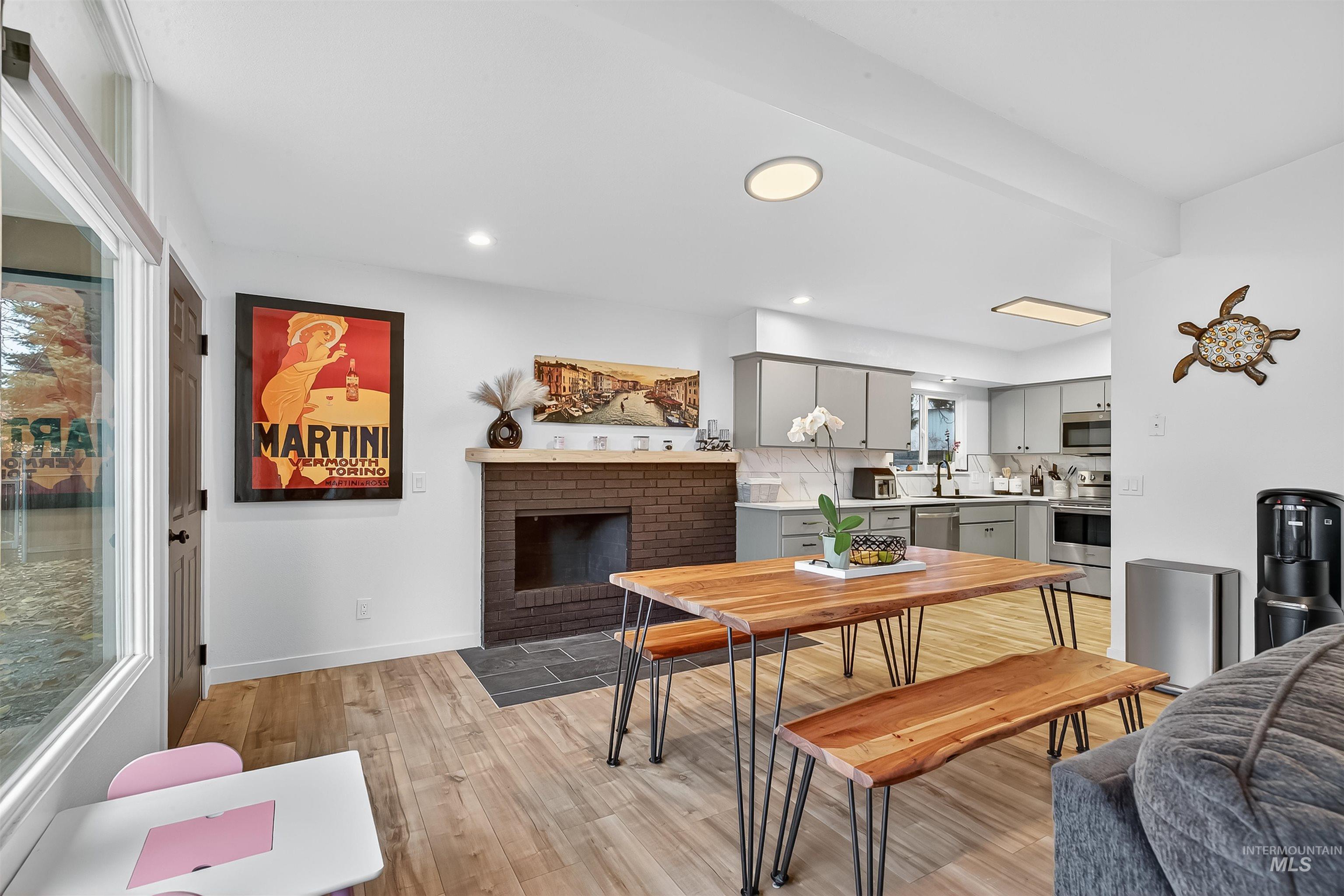 Dining room featuring light wood-style floors, a fireplace, recessed lighting, and beamed ceiling