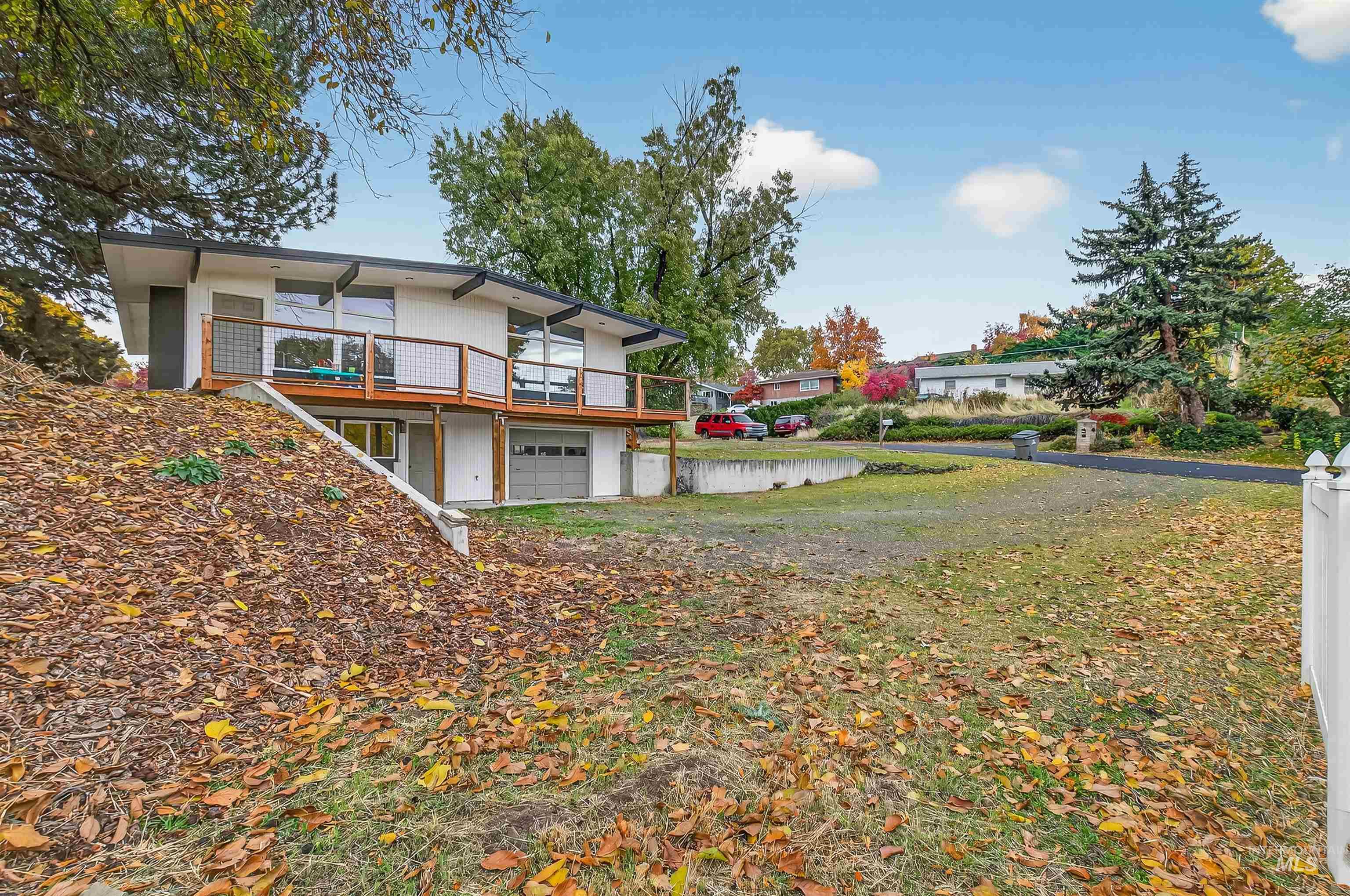 Rear view of property featuring a garage, a deck, and stucco siding