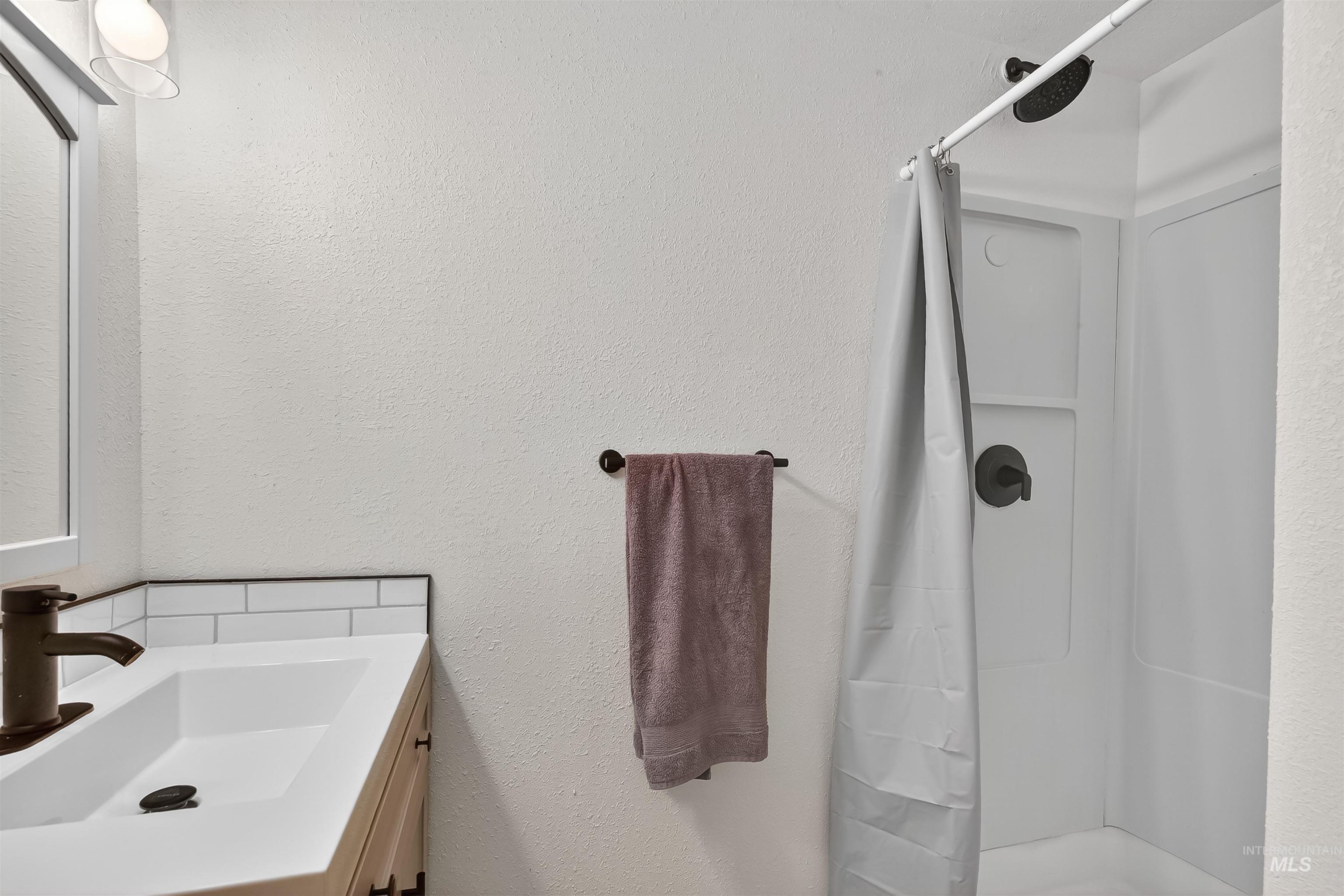Bathroom with vanity, a shower stall, and a textured wall