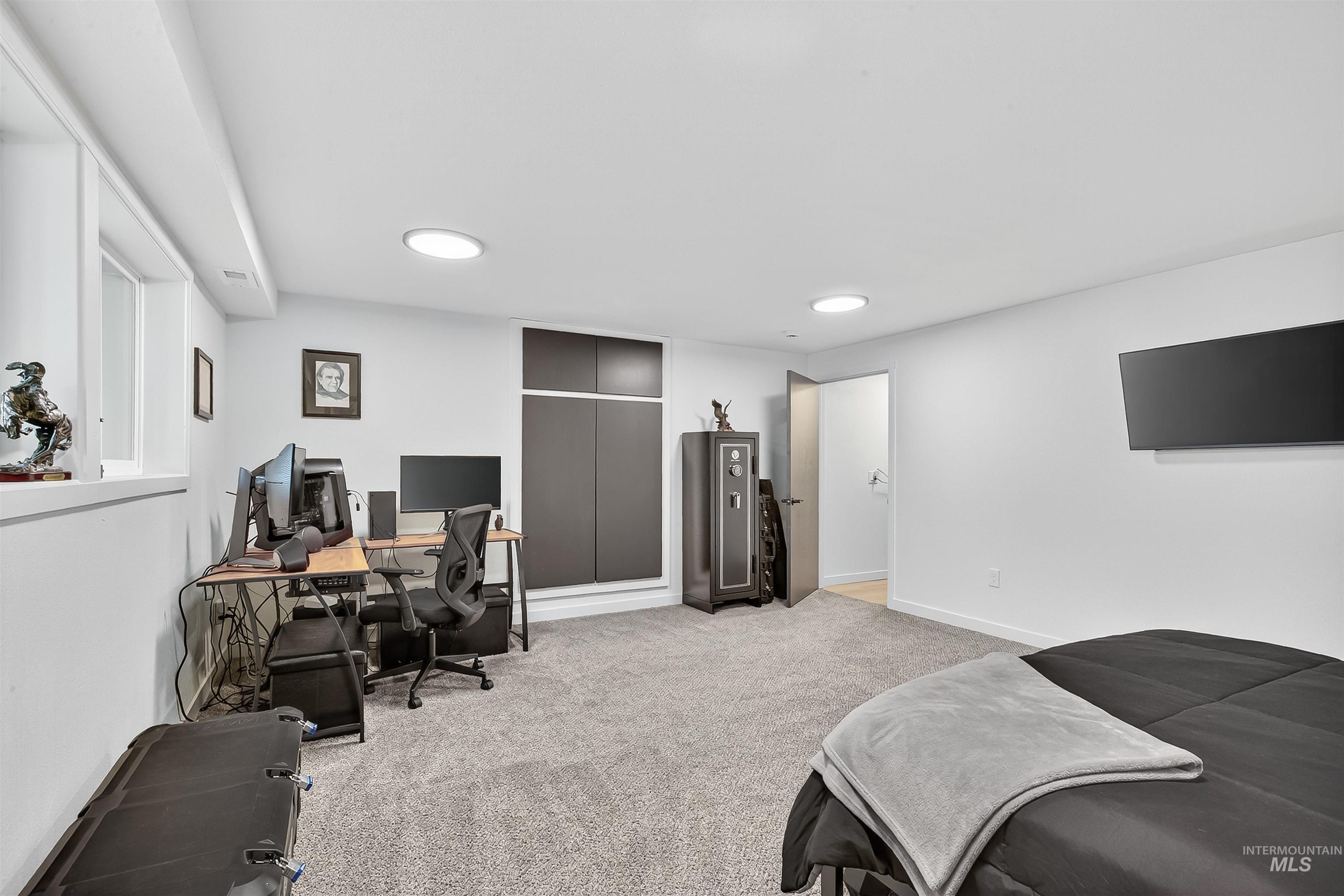 Bedroom with a closet, light colored carpet, and an office area