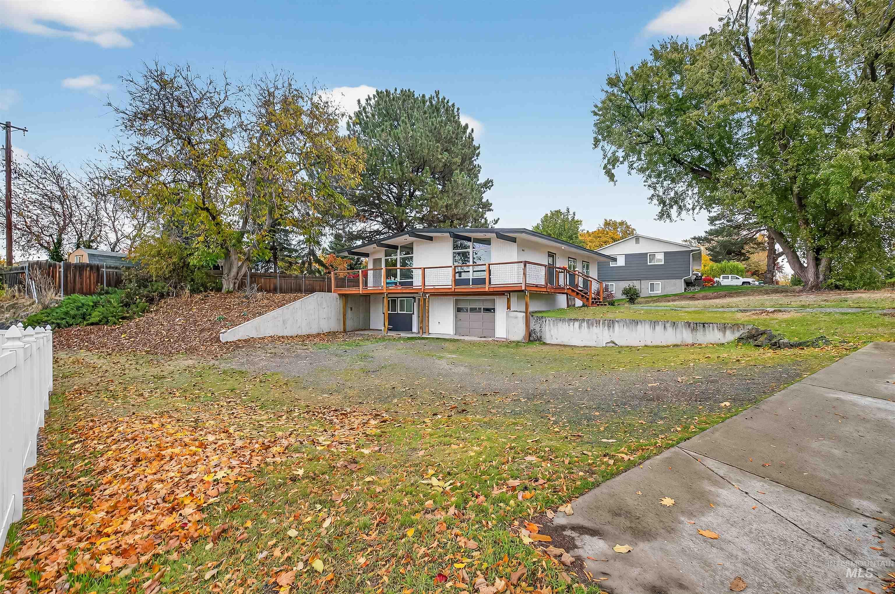 Back of property featuring a garage, a wooden deck, and stucco siding