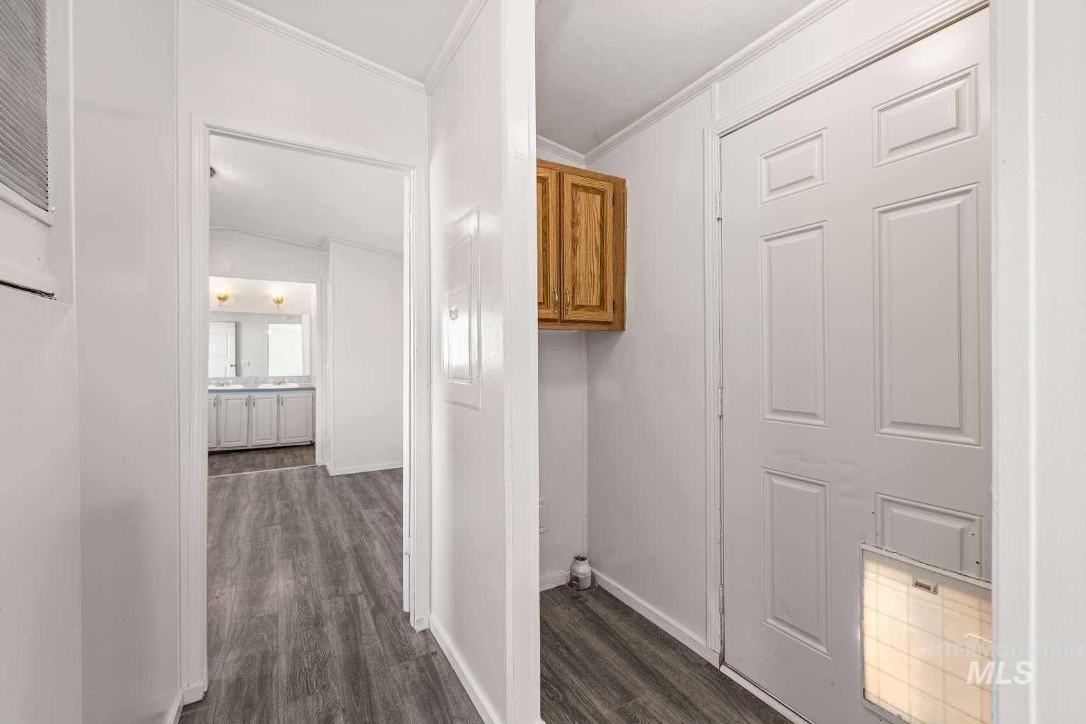 Corridor featuring dark wood-style floors and crown molding