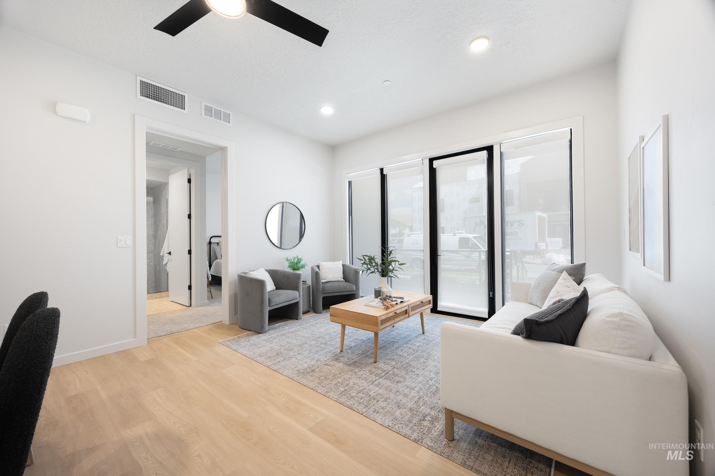 Living area with light wood-style floors, recessed lighting, and a ceiling fan