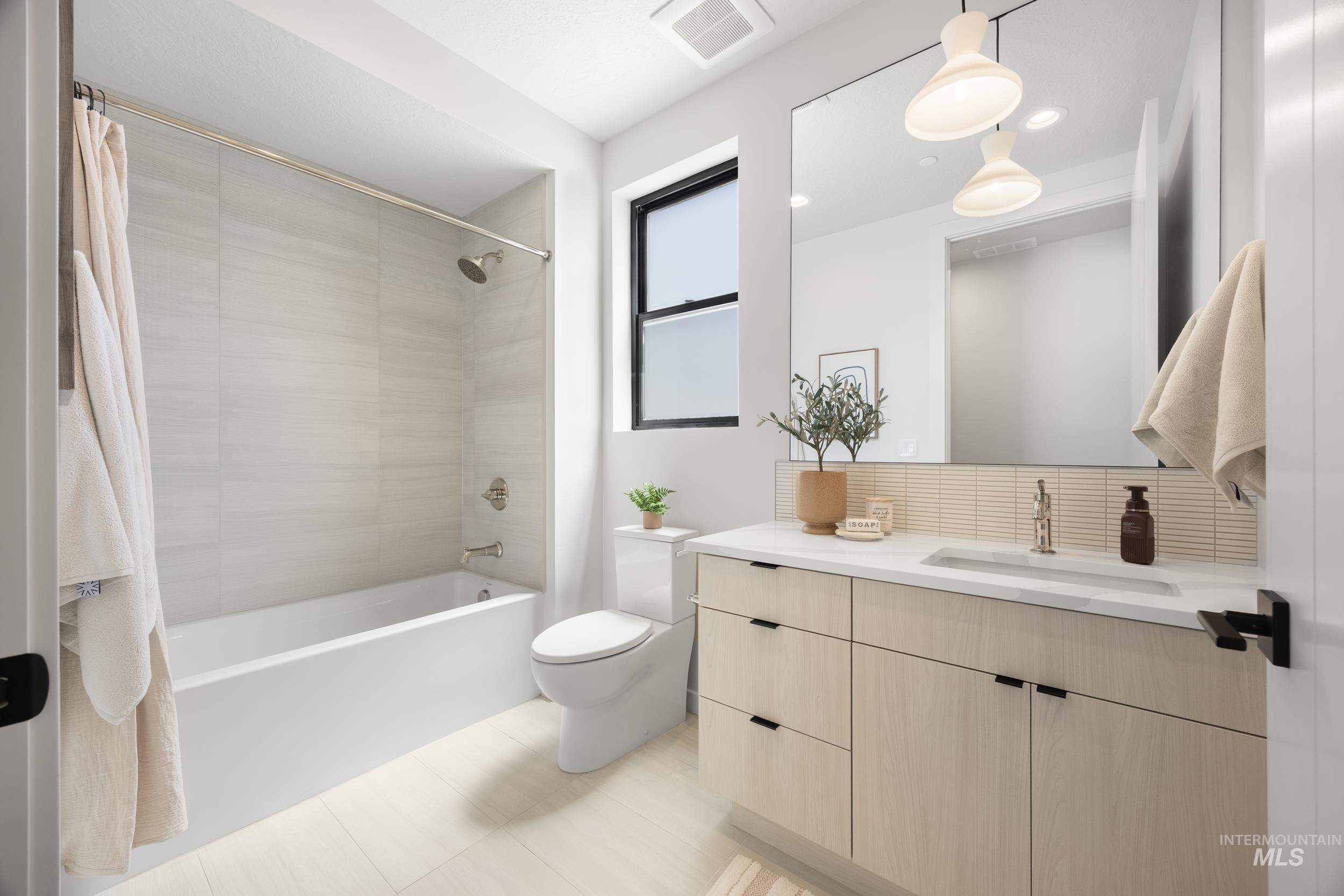 Full bath with shower / tub combo, vanity, backsplash, and light tile patterned flooring