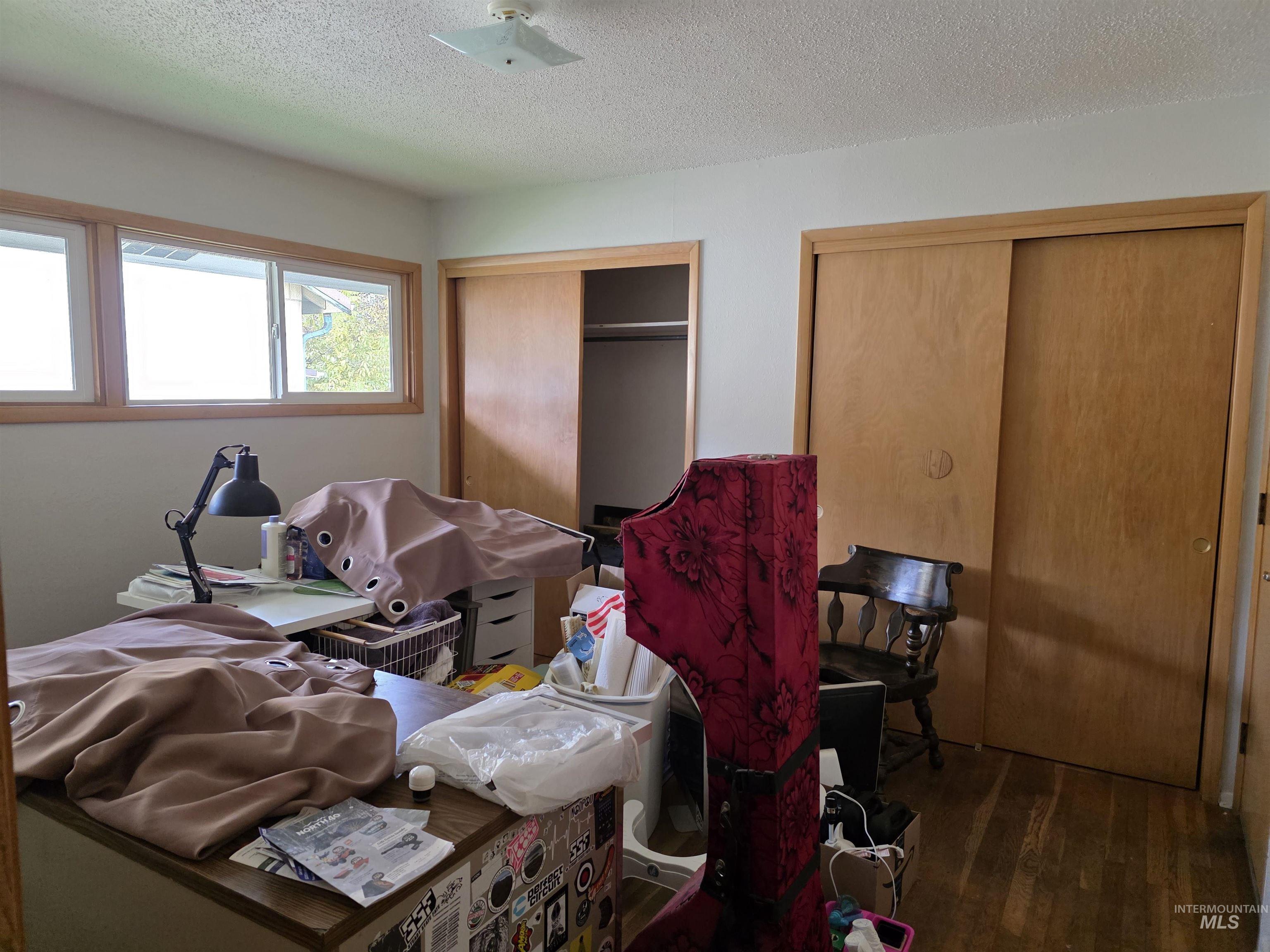Bedroom featuring two closets, a textured ceiling, and dark wood-style floors