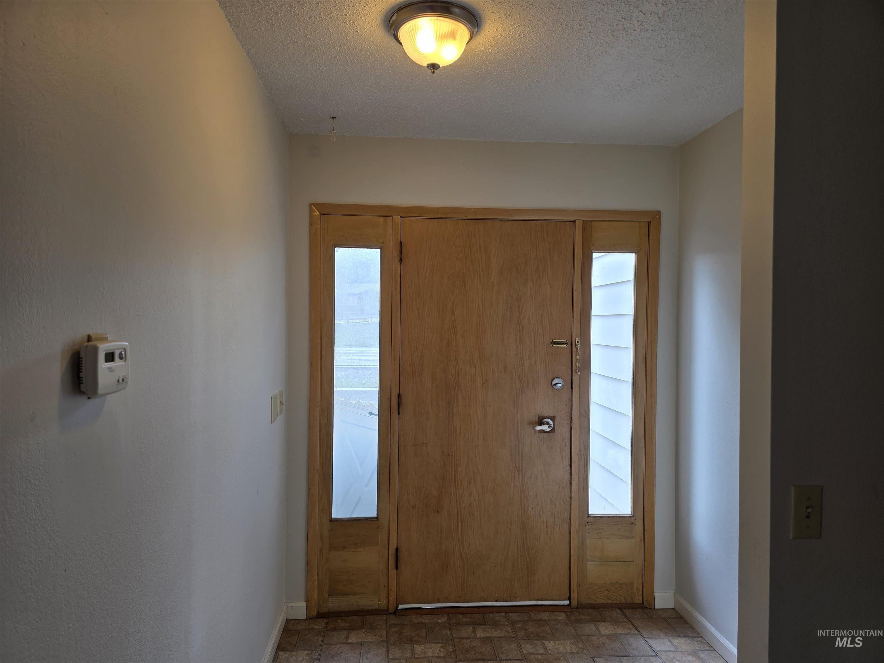 Foyer entrance featuring baseboards and a textured ceiling