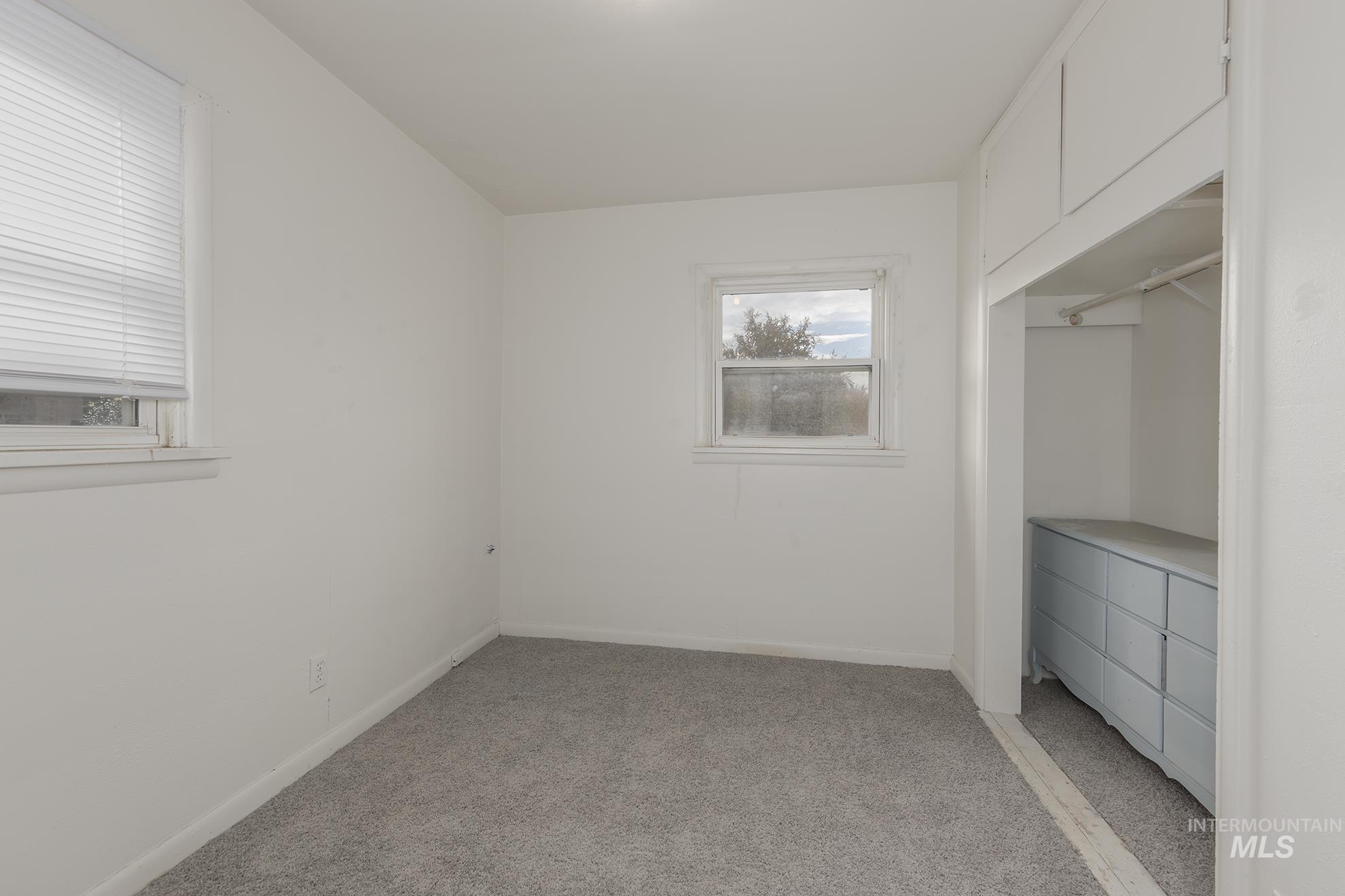 Unfurnished bedroom with light colored carpet and baseboards