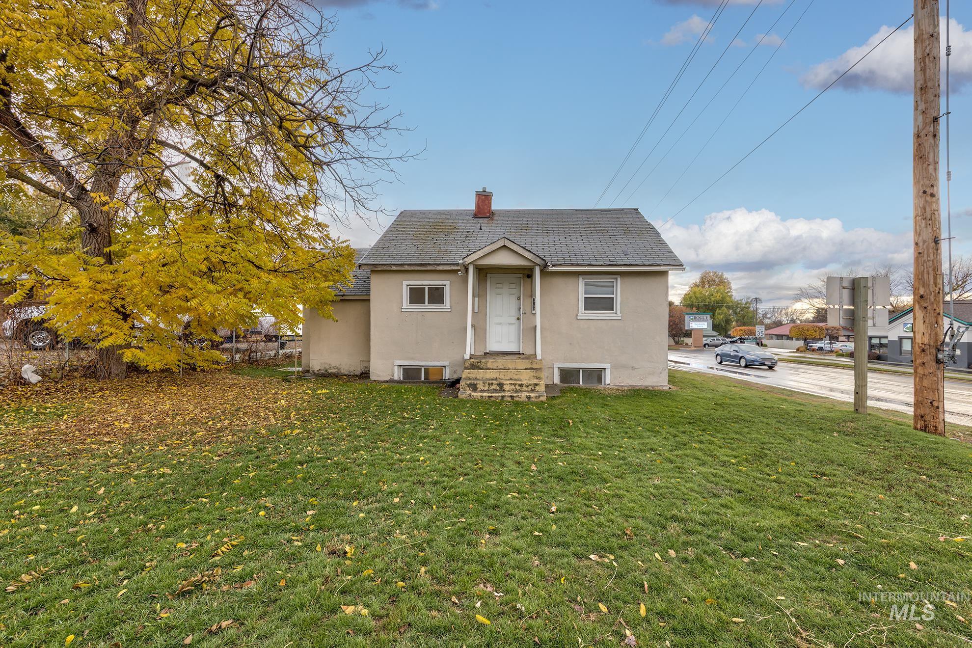 View of front of house with stucco siding, a chimney, a front yard, and roof with shingles