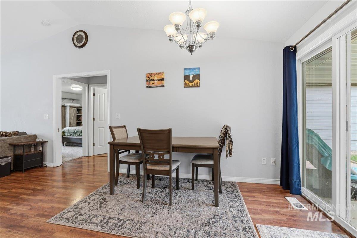 Dining room with vaulted ceiling, a chandelier, and wood finished floors