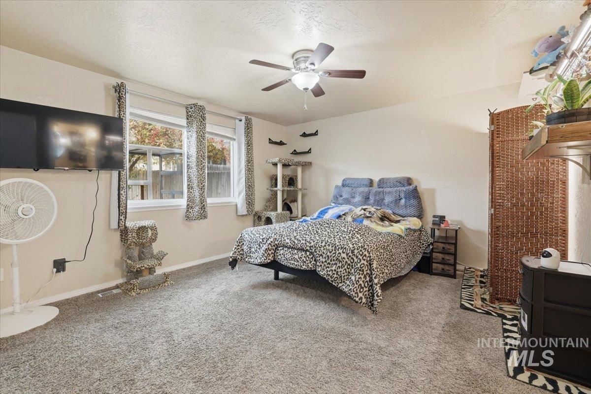Carpeted bedroom with a ceiling fan and a textured ceiling