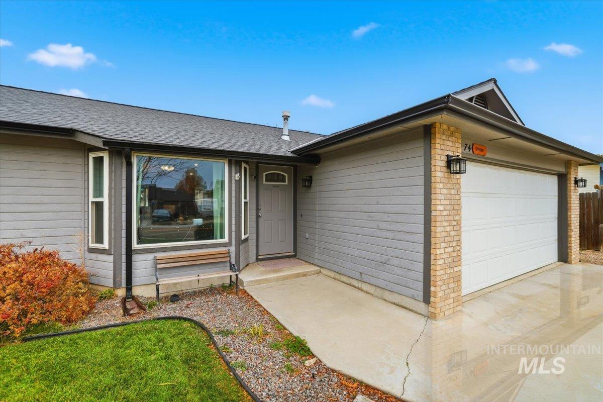View of front facade with a garage, brick siding, and roof with shingles