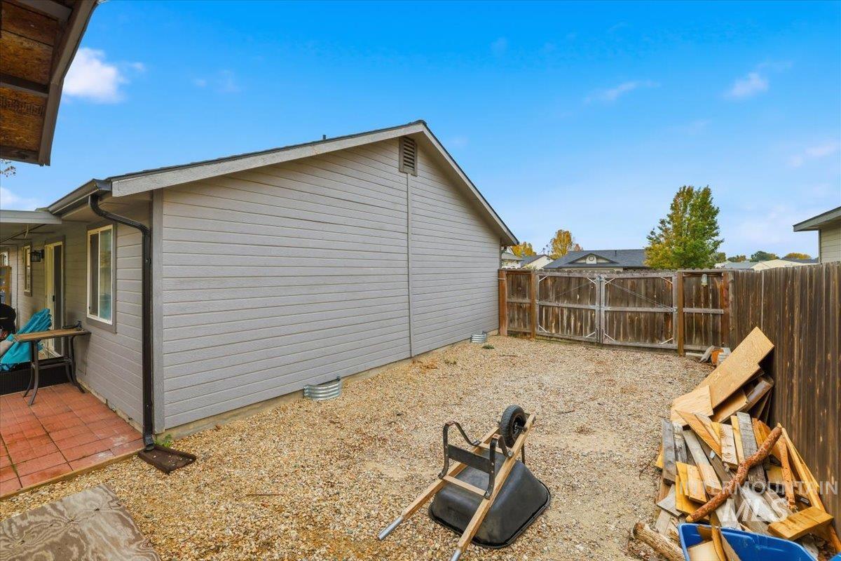 View of side of home featuring a patio and a gate
