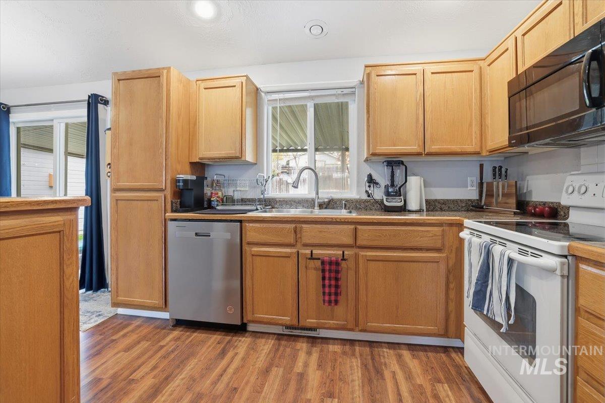 Kitchen featuring electric stove, black microwave, light wood finished floors, stainless steel dishwasher, and recessed lighting