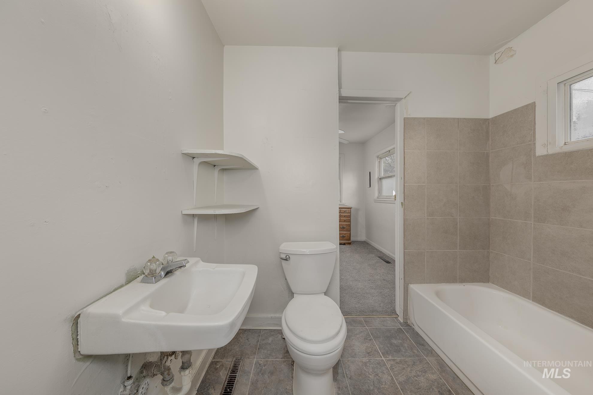 Bathroom featuring plenty of natural light, tile patterned flooring, and bathtub / shower combination