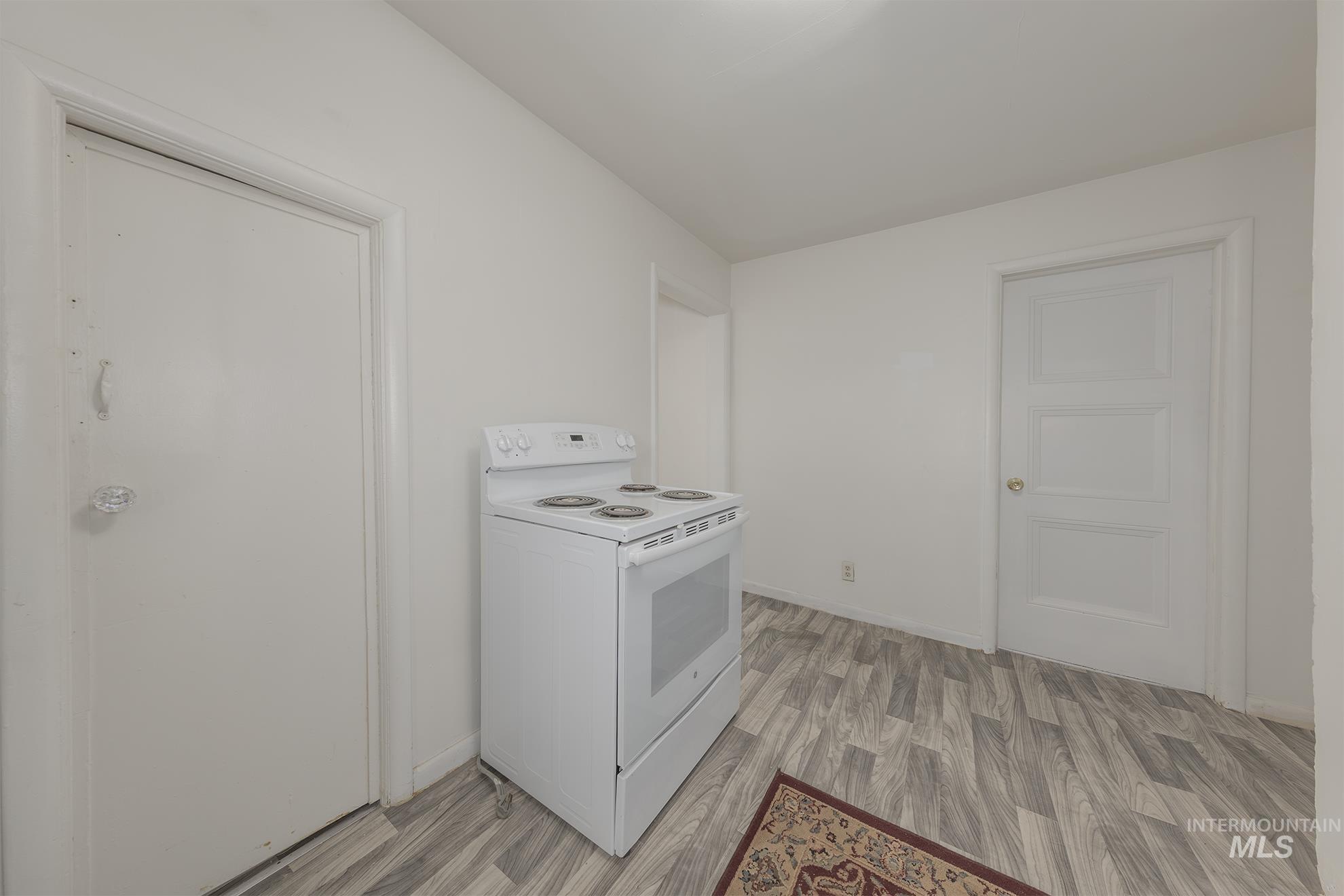 Kitchen with white range with electric stovetop, light wood-type flooring, and white cabinetry