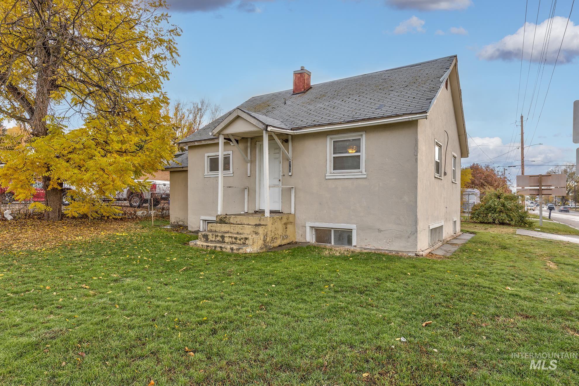 Back of house featuring stucco siding, a yard, a shingled roof, and a chimney