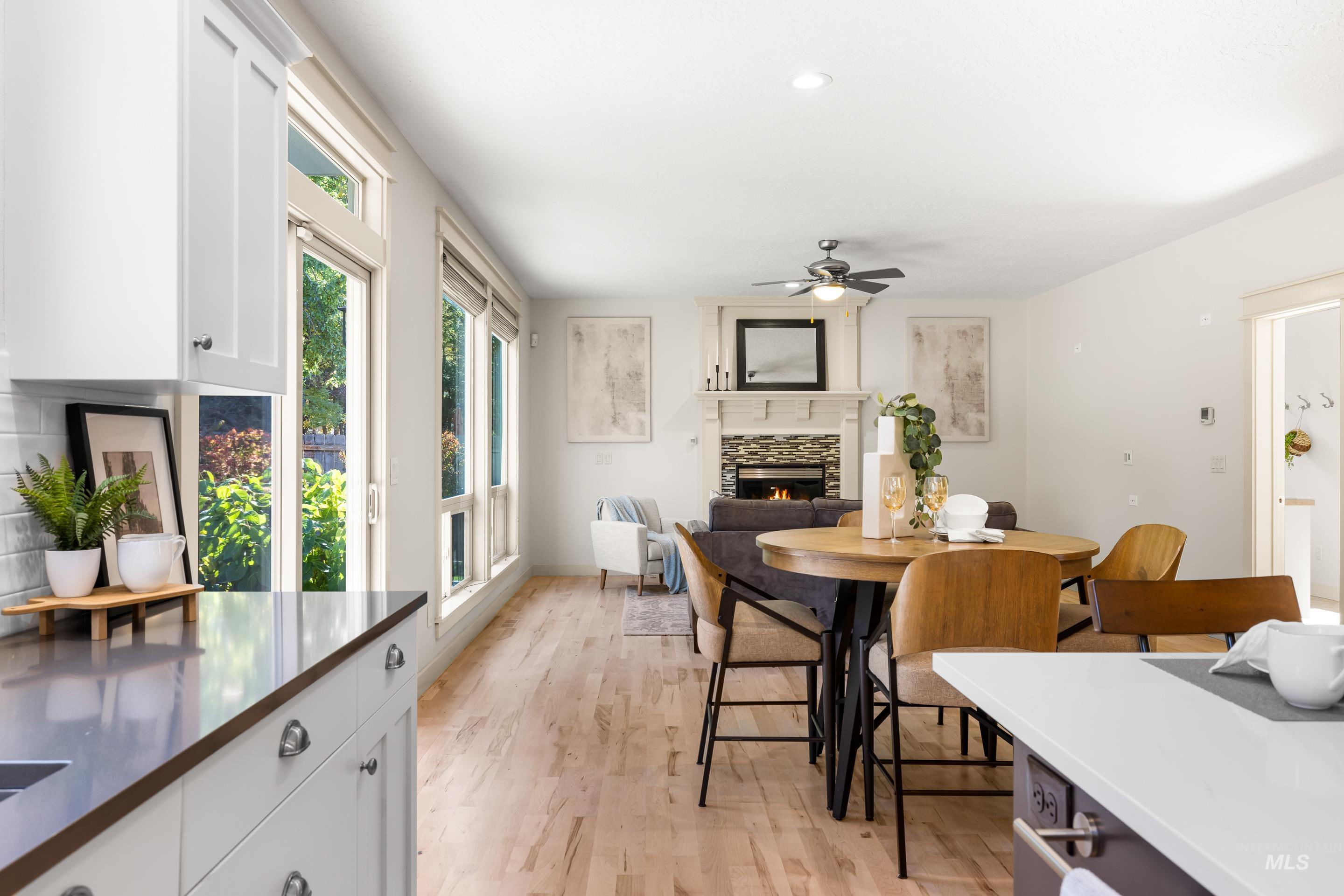 Dining room featuring a tiled fireplace, light wood-style flooring, and ceiling fan