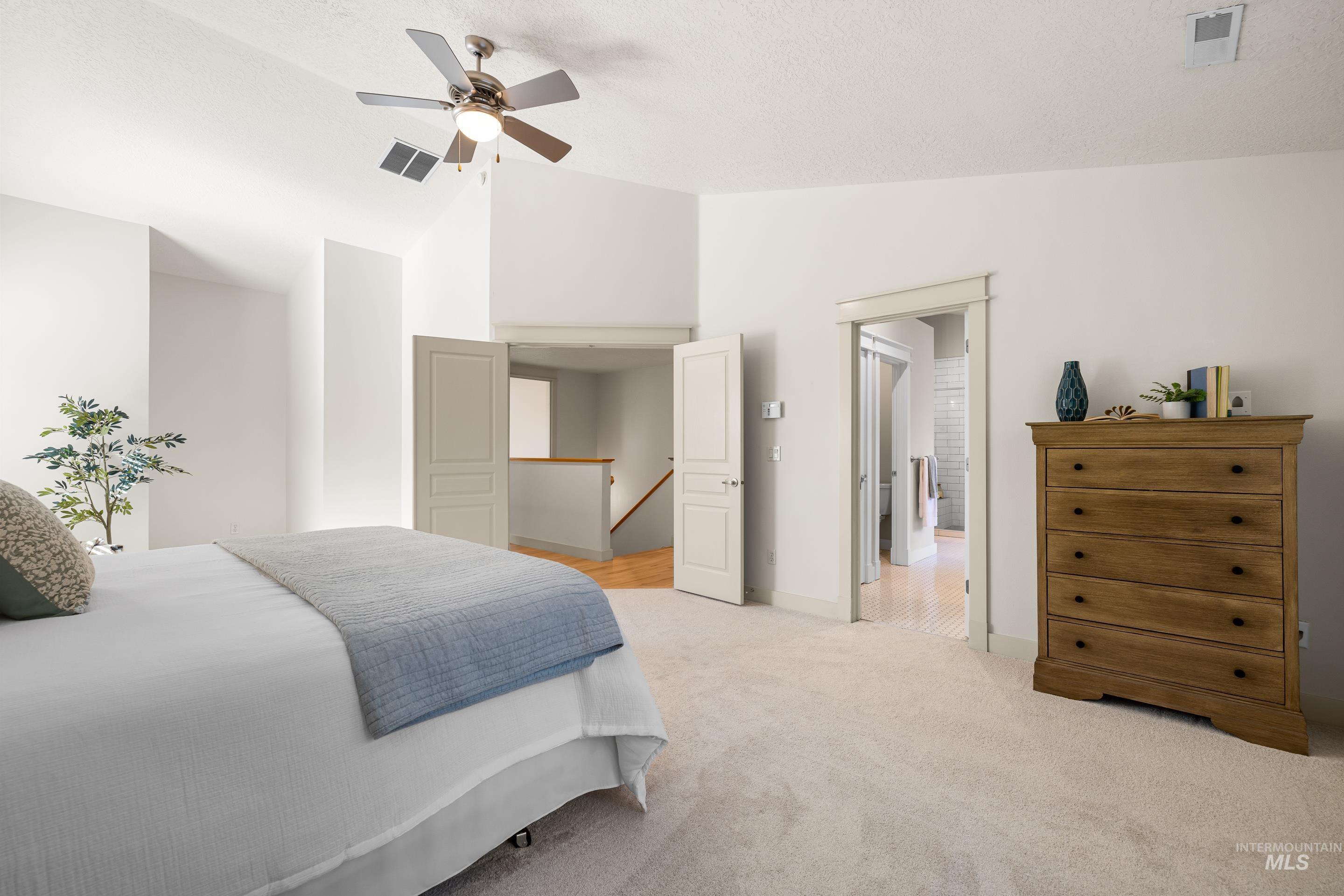 Bedroom with lofted ceiling, light colored carpet, and a ceiling fan
