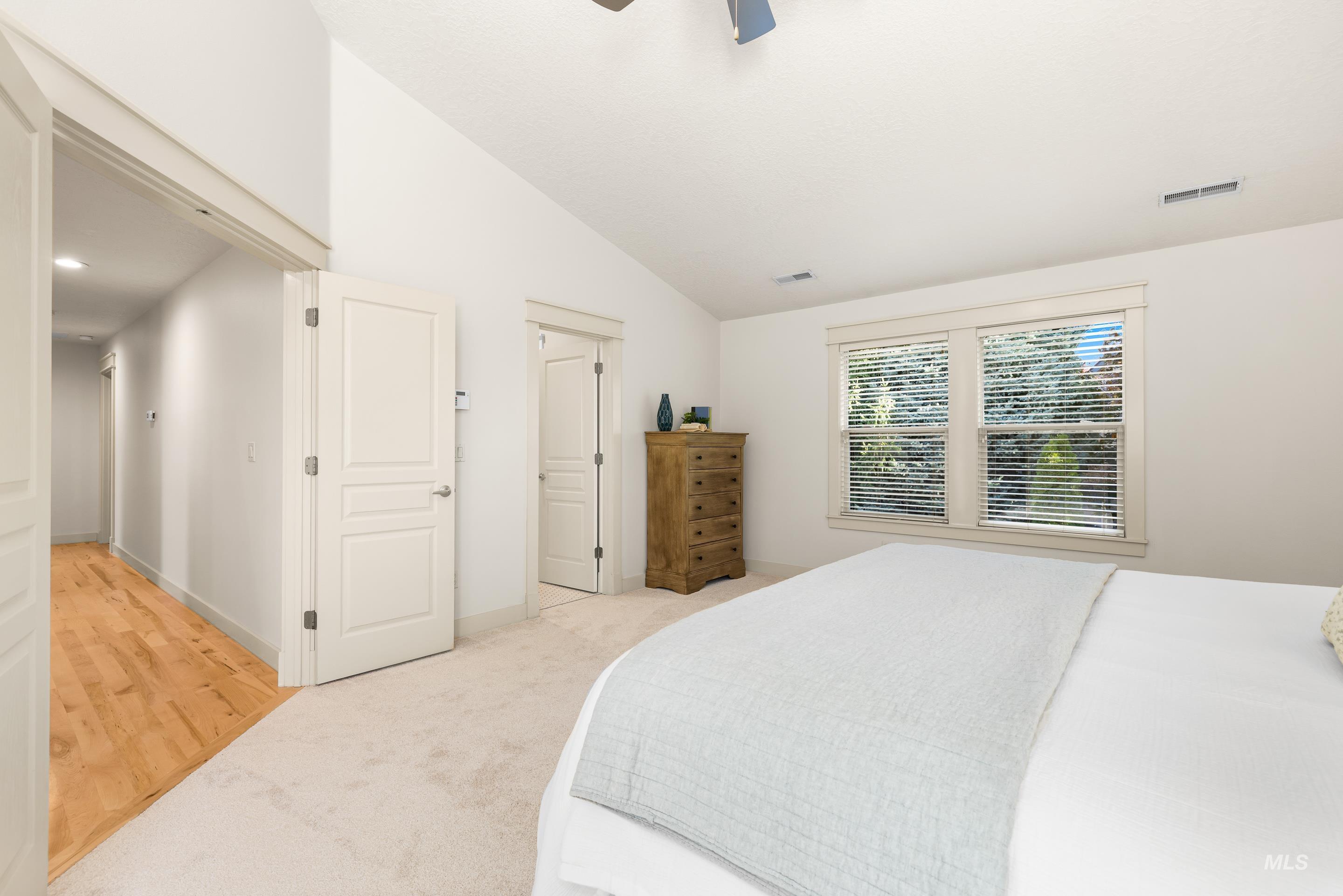 Bedroom featuring vaulted ceiling, light carpet, a ceiling fan, light wood-type flooring, and a closet