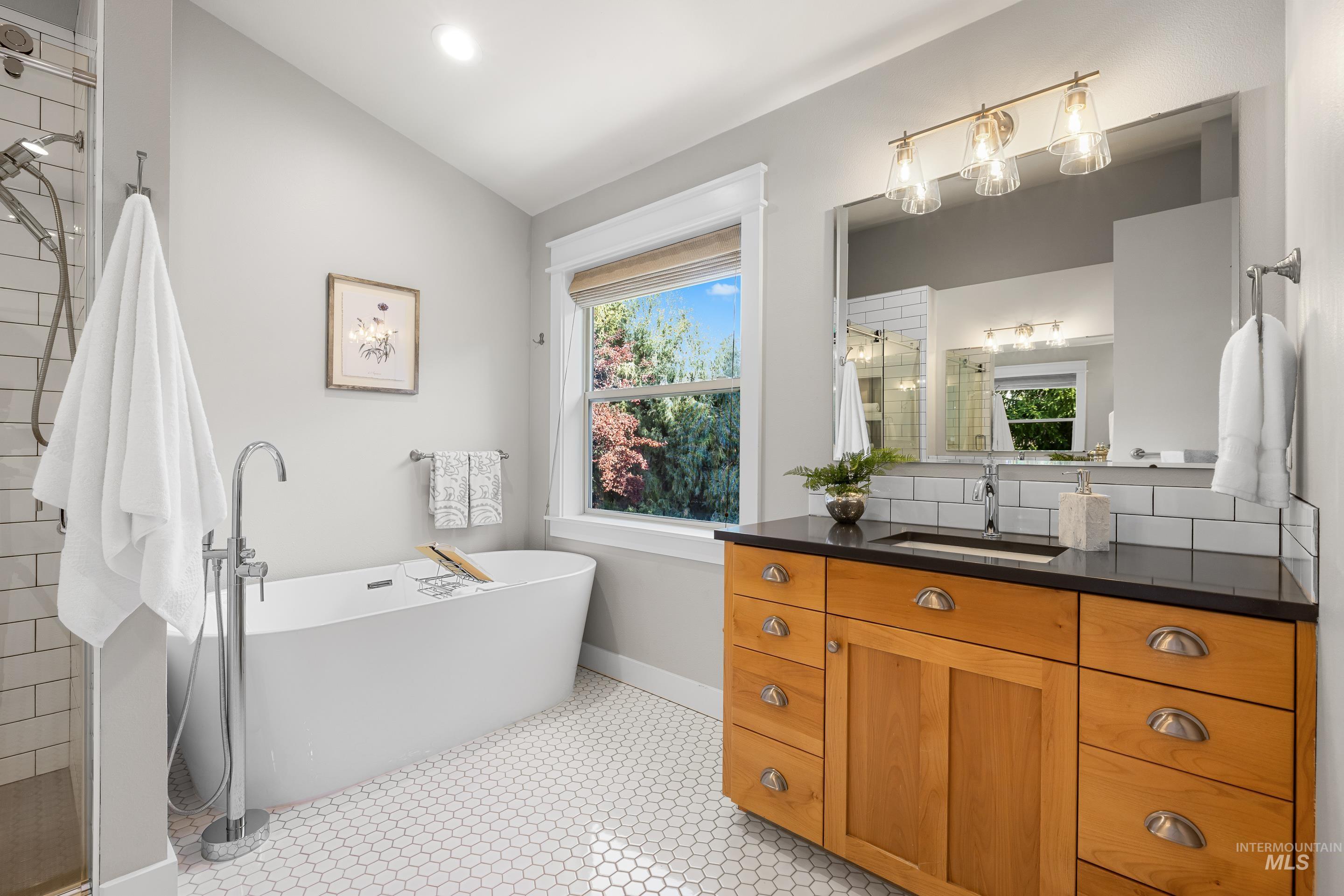 Bathroom with vanity, a freestanding bath, healthy amount of natural light, tiled shower, and recessed lighting