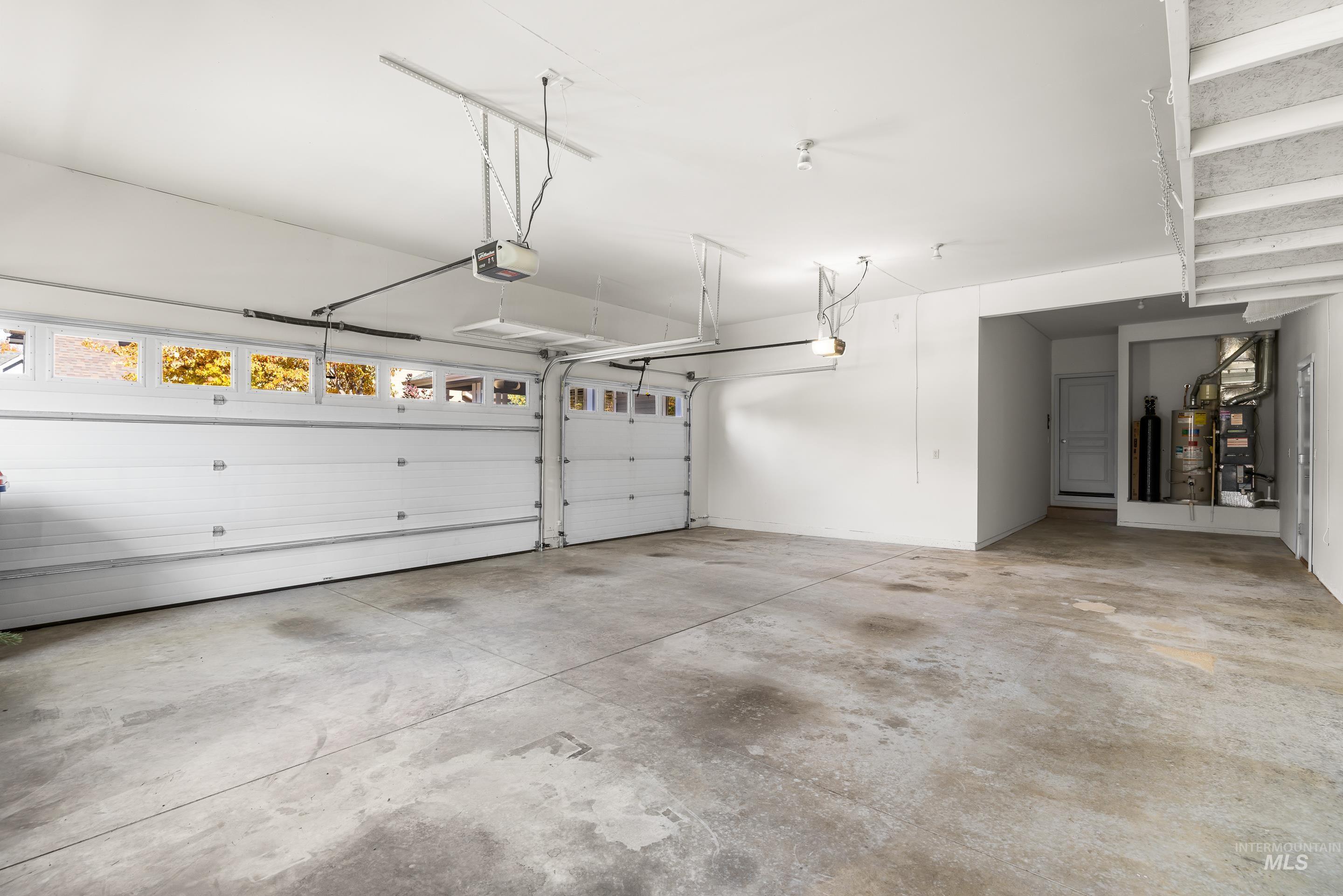 Garage featuring water heater, heating unit, and a garage door opener