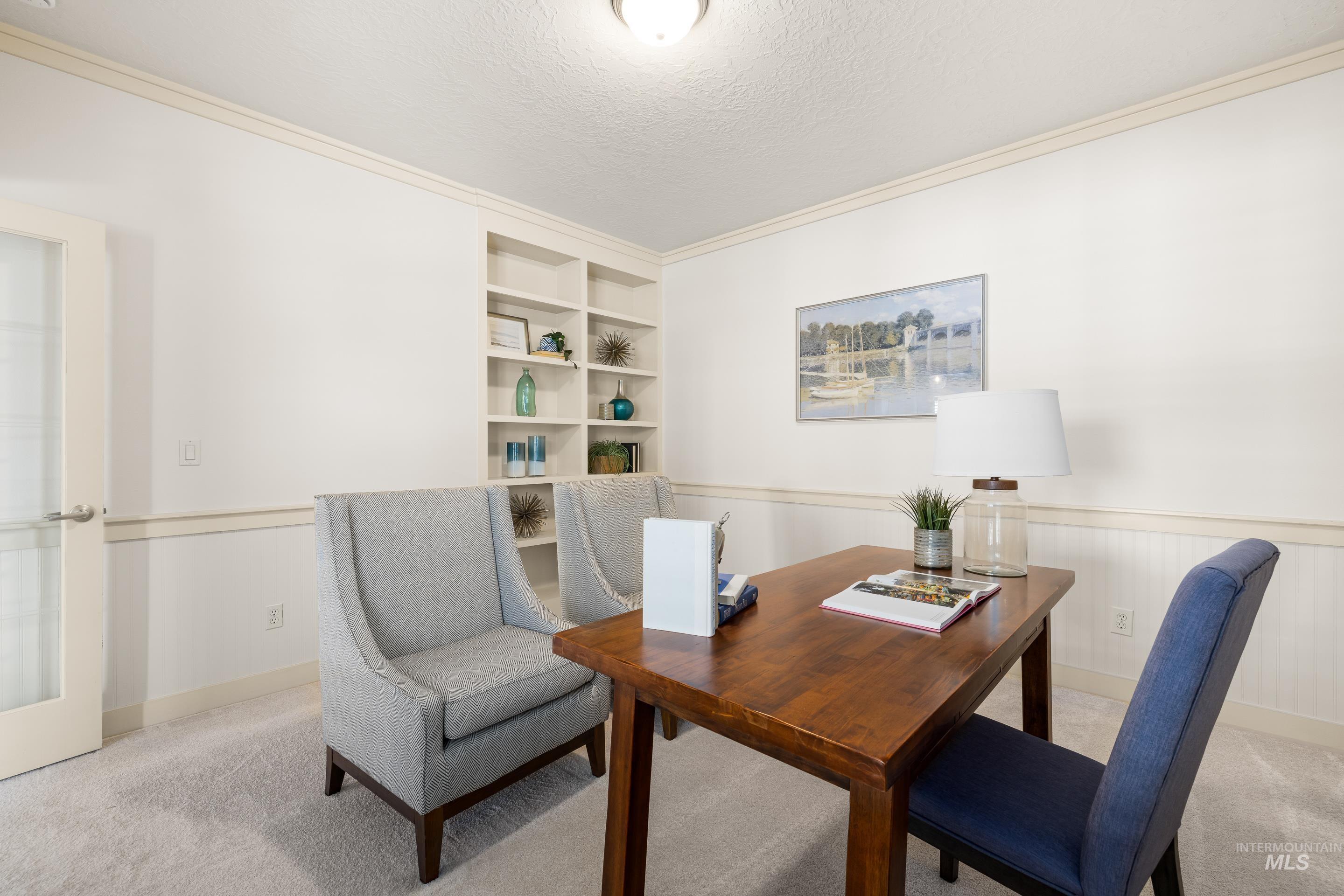 Carpeted home office with built in shelves, a textured ceiling, and crown molding
