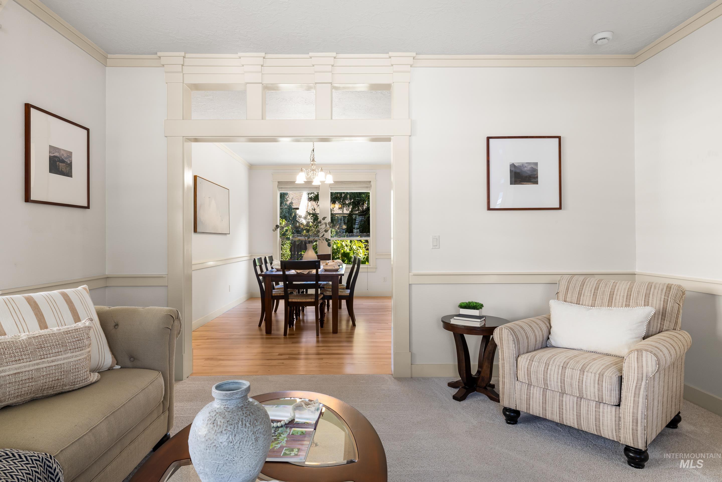 Living room featuring crown molding, a chandelier, wood finished floors, and carpet