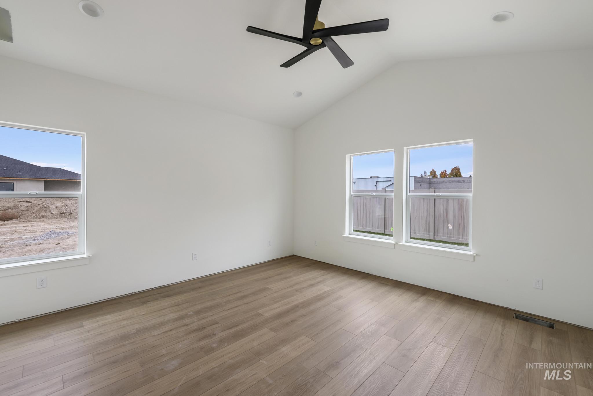 Unfurnished room featuring lofted ceiling, light wood finished floors, and ceiling fan