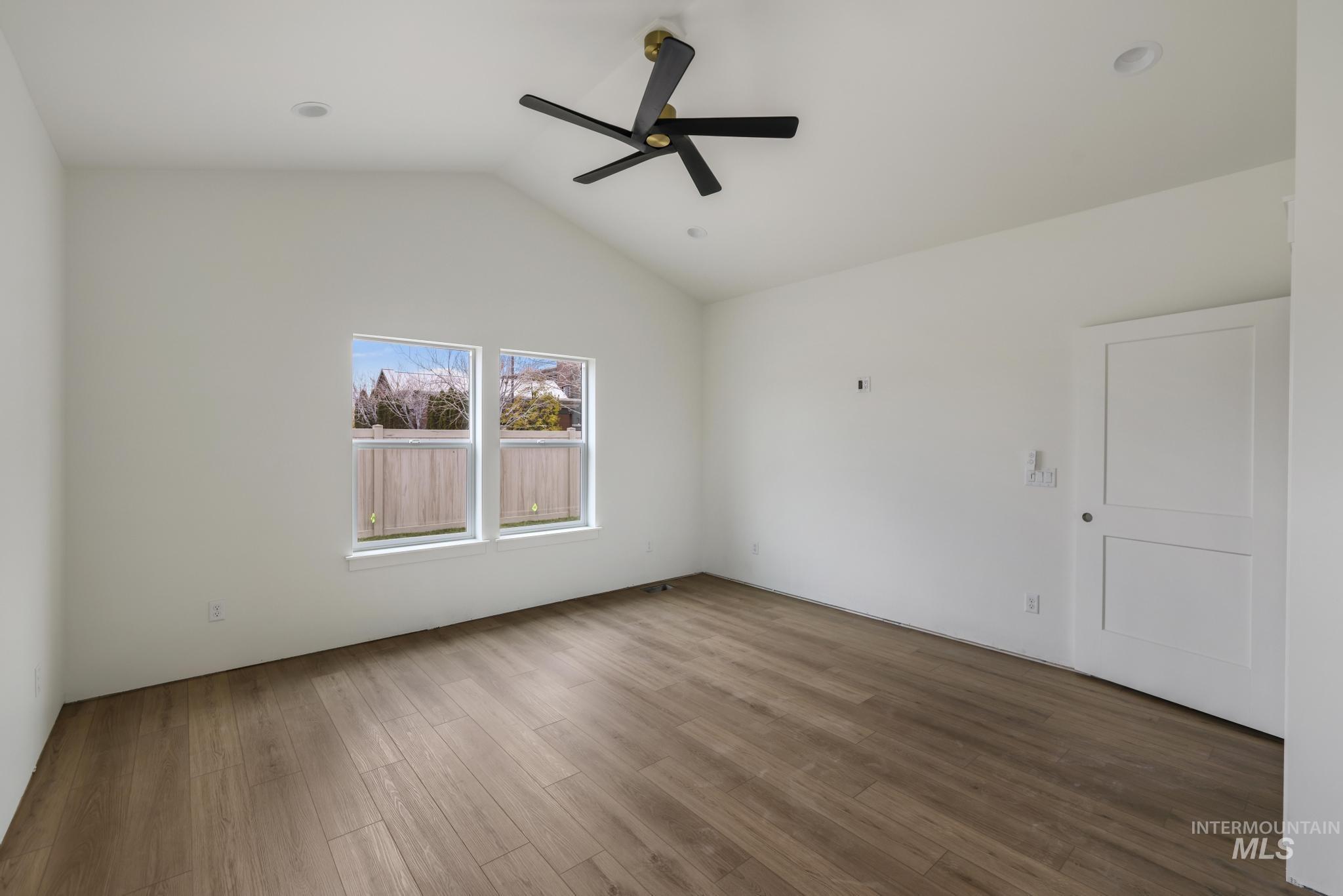 Spare room with vaulted ceiling, wood finished floors, and ceiling fan
