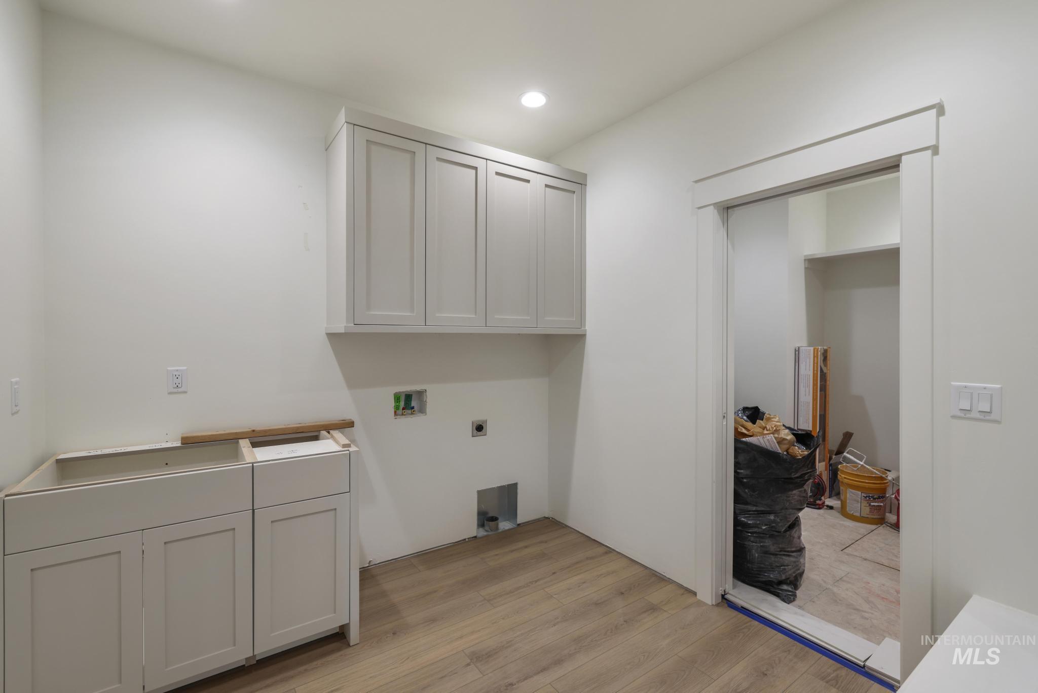 Laundry room with light wood-style floors, cabinet space, washer hookup, recessed lighting, and hookup for an electric dryer