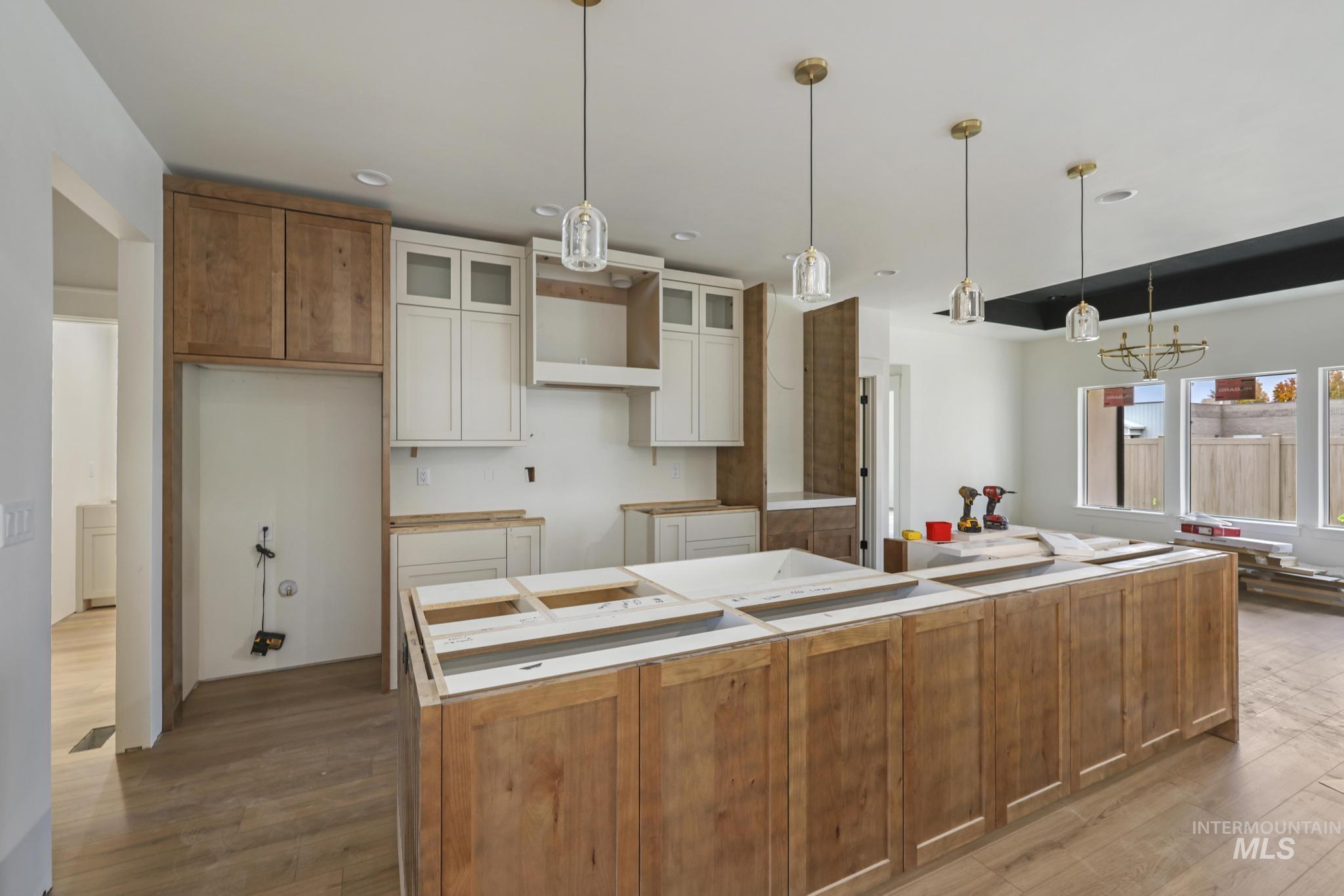 Kitchen with hanging light fixtures, a center island, dark wood-type flooring, glass insert cabinets, and white cabinets