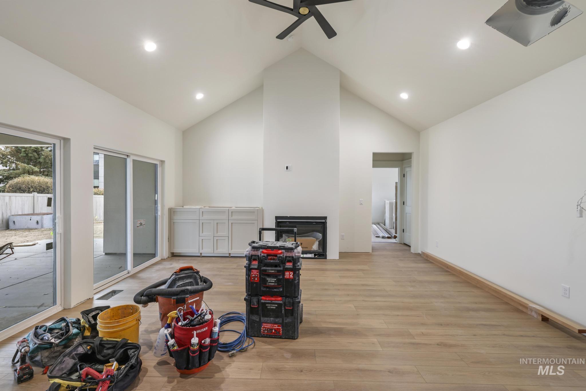 Living area featuring high vaulted ceiling, light wood-style floors, recessed lighting, and a ceiling fan