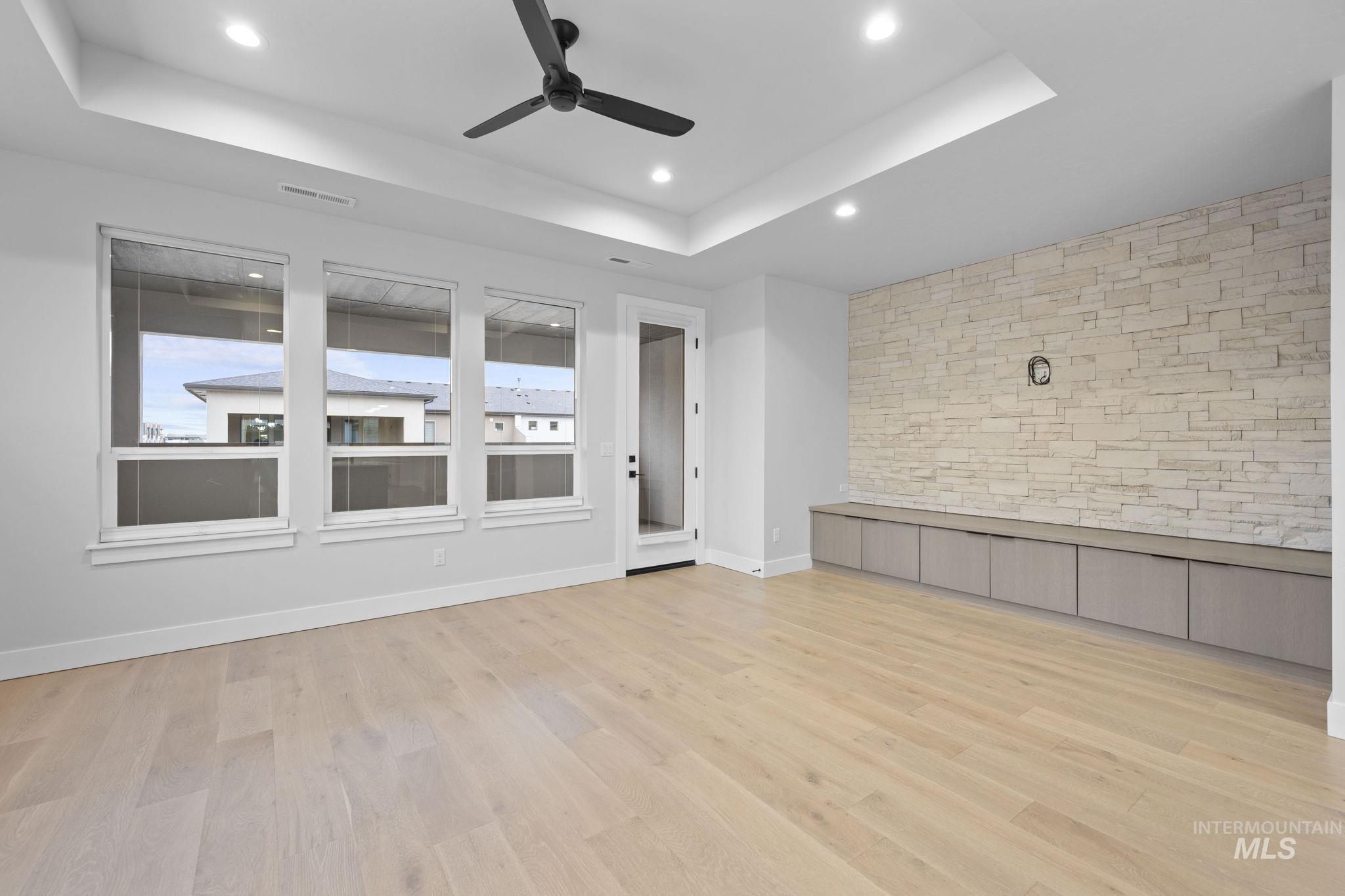 Spare room with a raised ceiling, light wood-style floors, ceiling fan, and recessed lighting