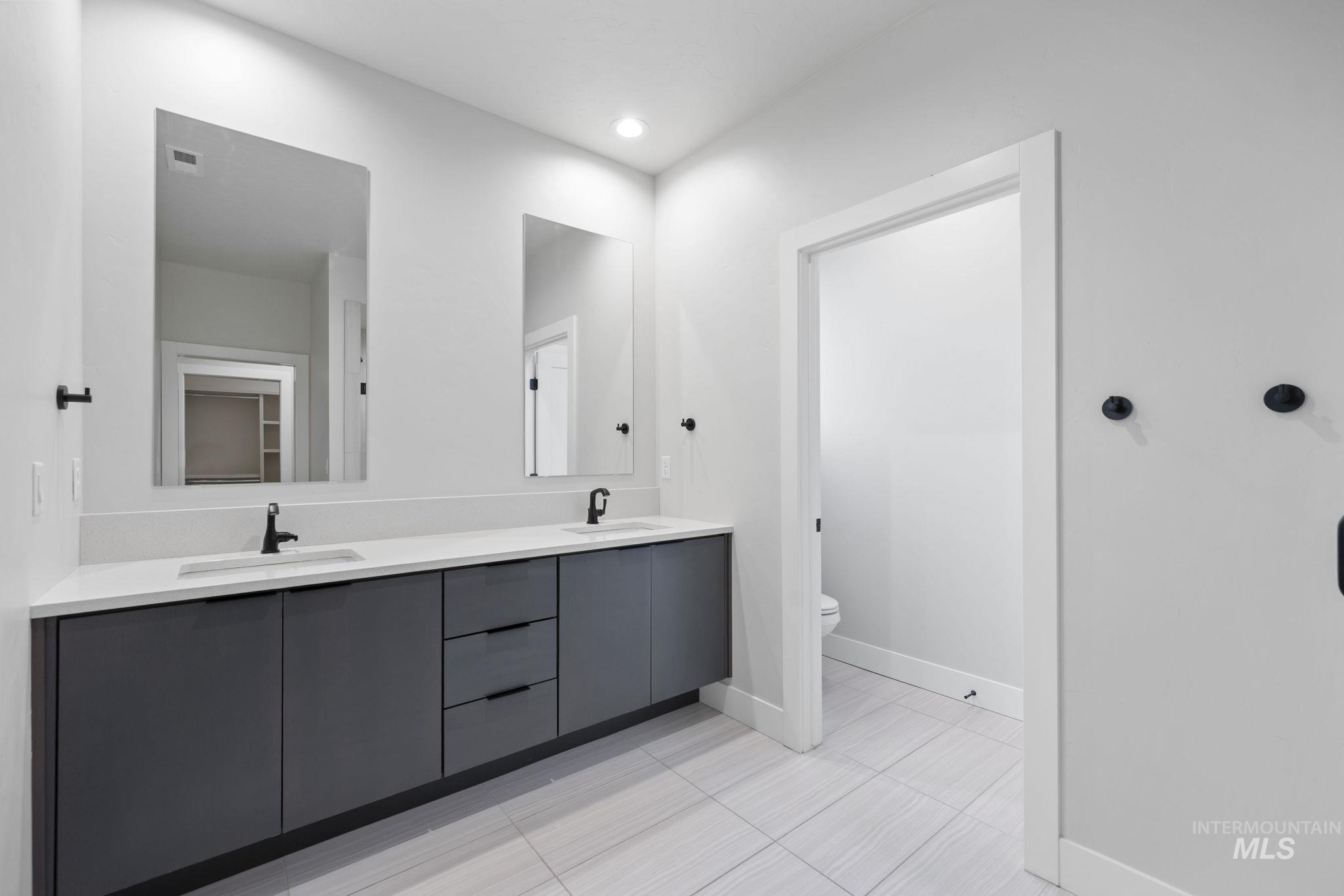 Bathroom with double vanity, light tile patterned flooring, and recessed lighting