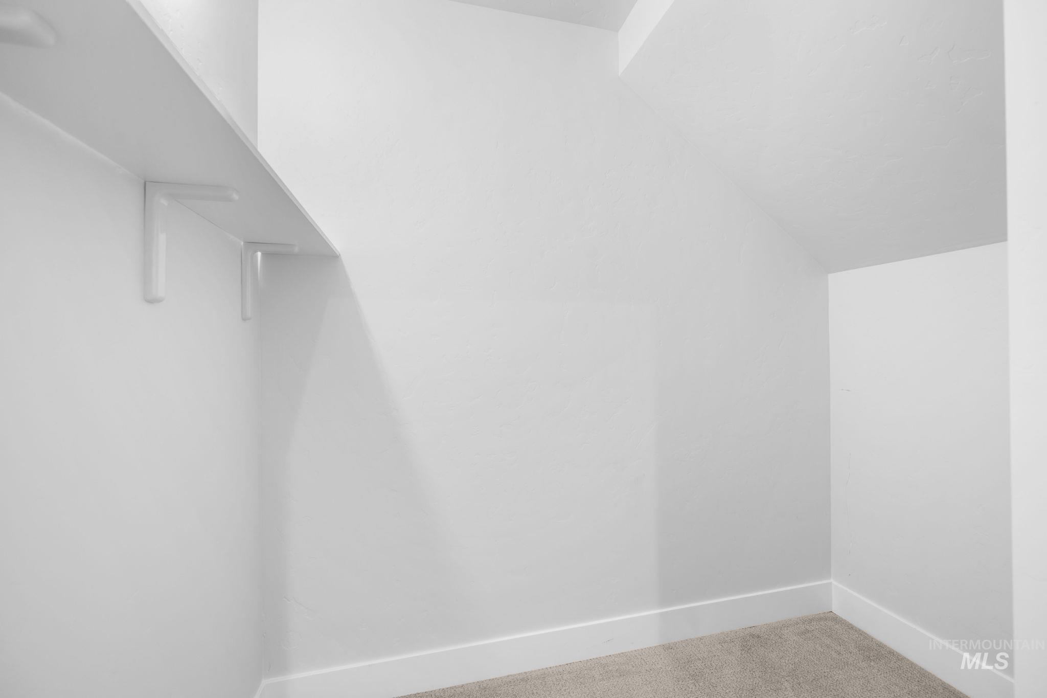 Walk in closet with lofted ceiling and carpet floors