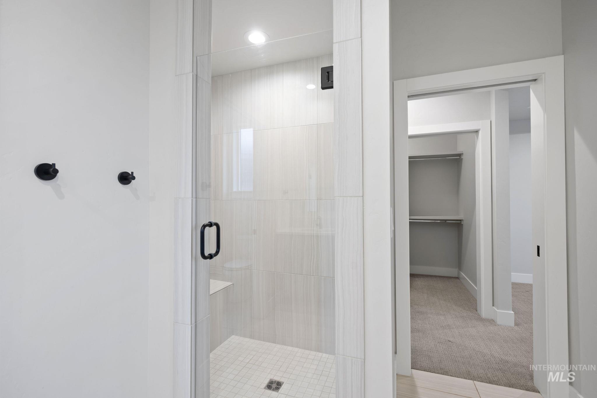 Full bath featuring a spacious closet, a shower stall, light colored carpet, and recessed lighting