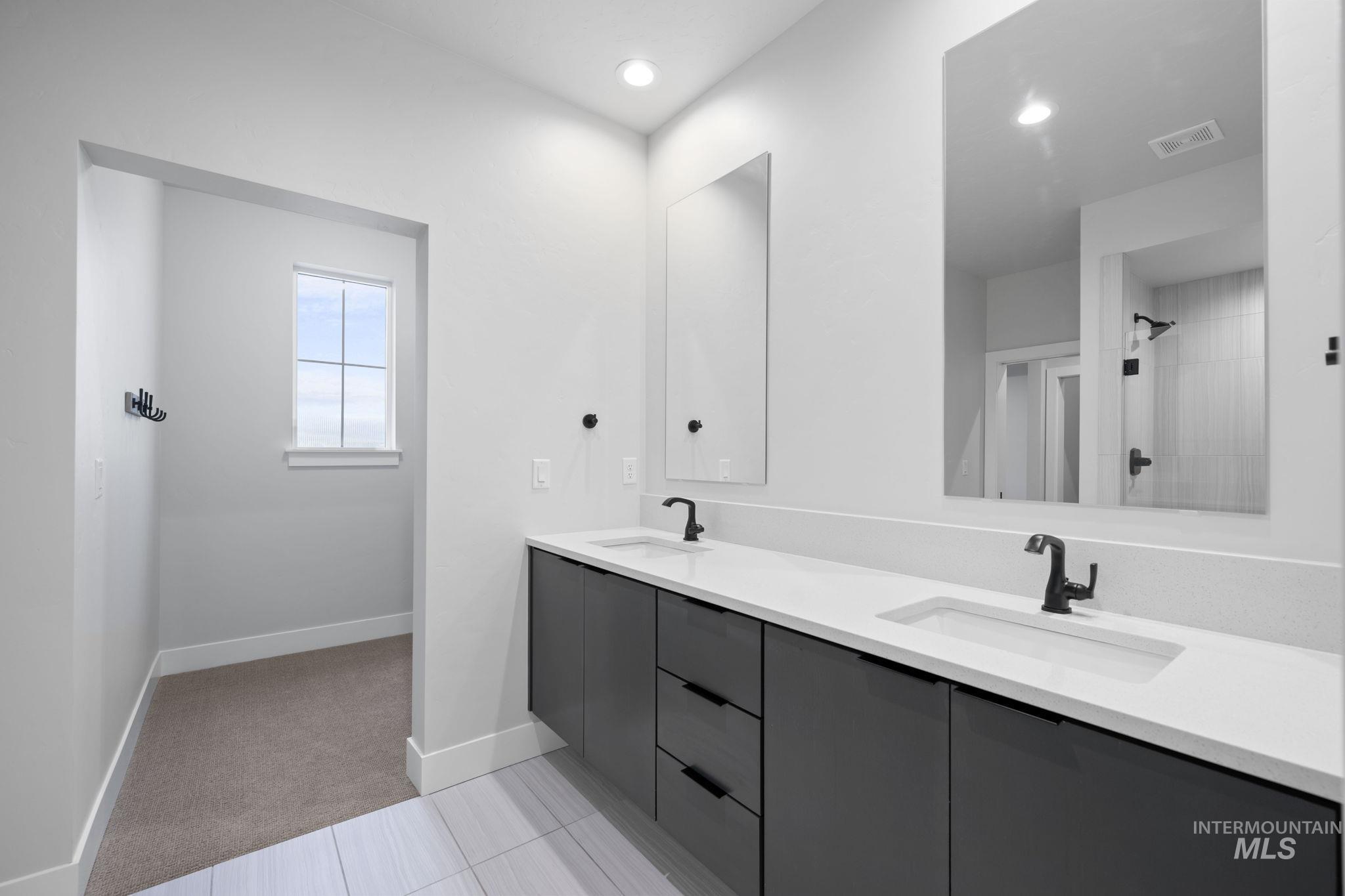 Bathroom featuring double vanity, light carpet, light tile patterned floors, a shower, and recessed lighting