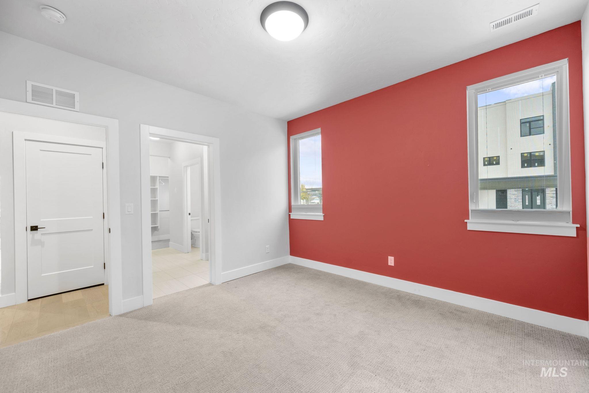 Unfurnished bedroom featuring light colored carpet and connected bathroom
