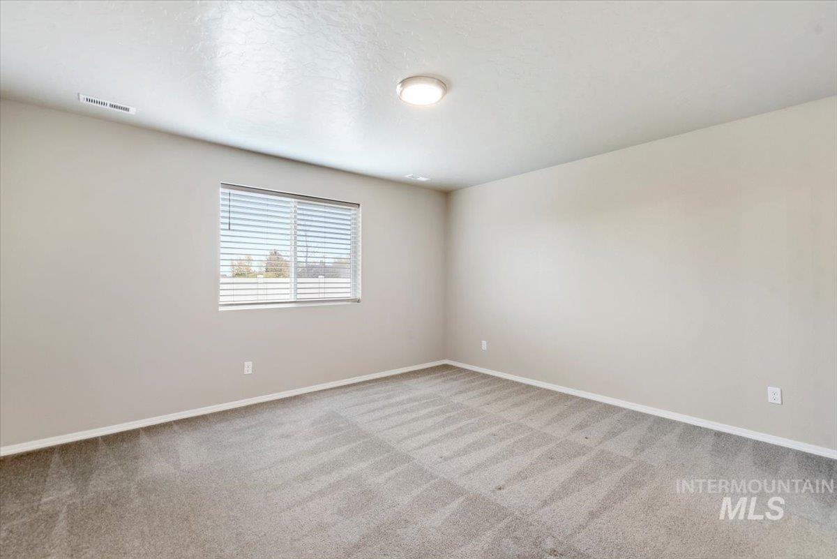 Carpeted empty room featuring baseboards and a textured ceiling