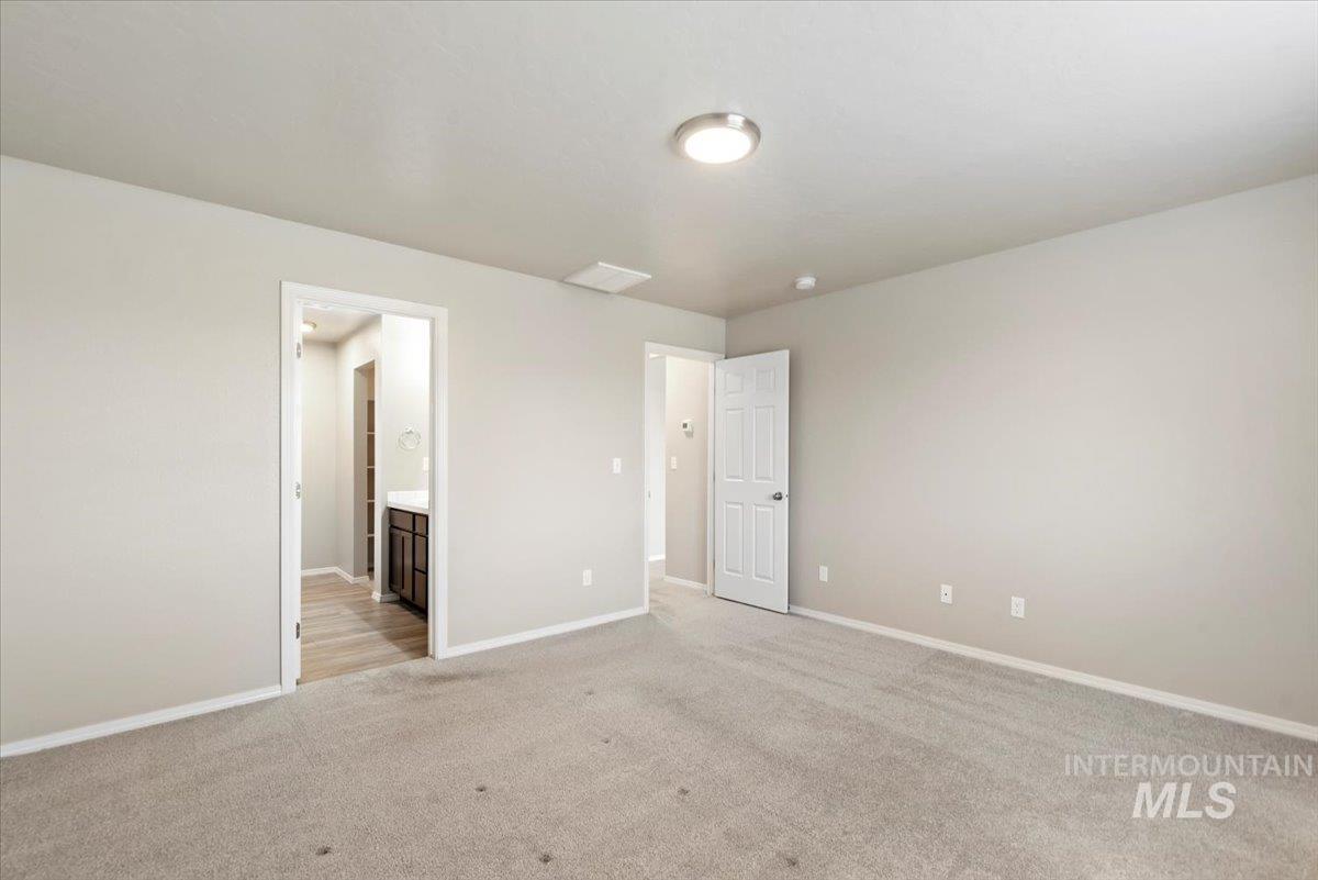Unfurnished bedroom featuring light carpet and ensuite bathroom