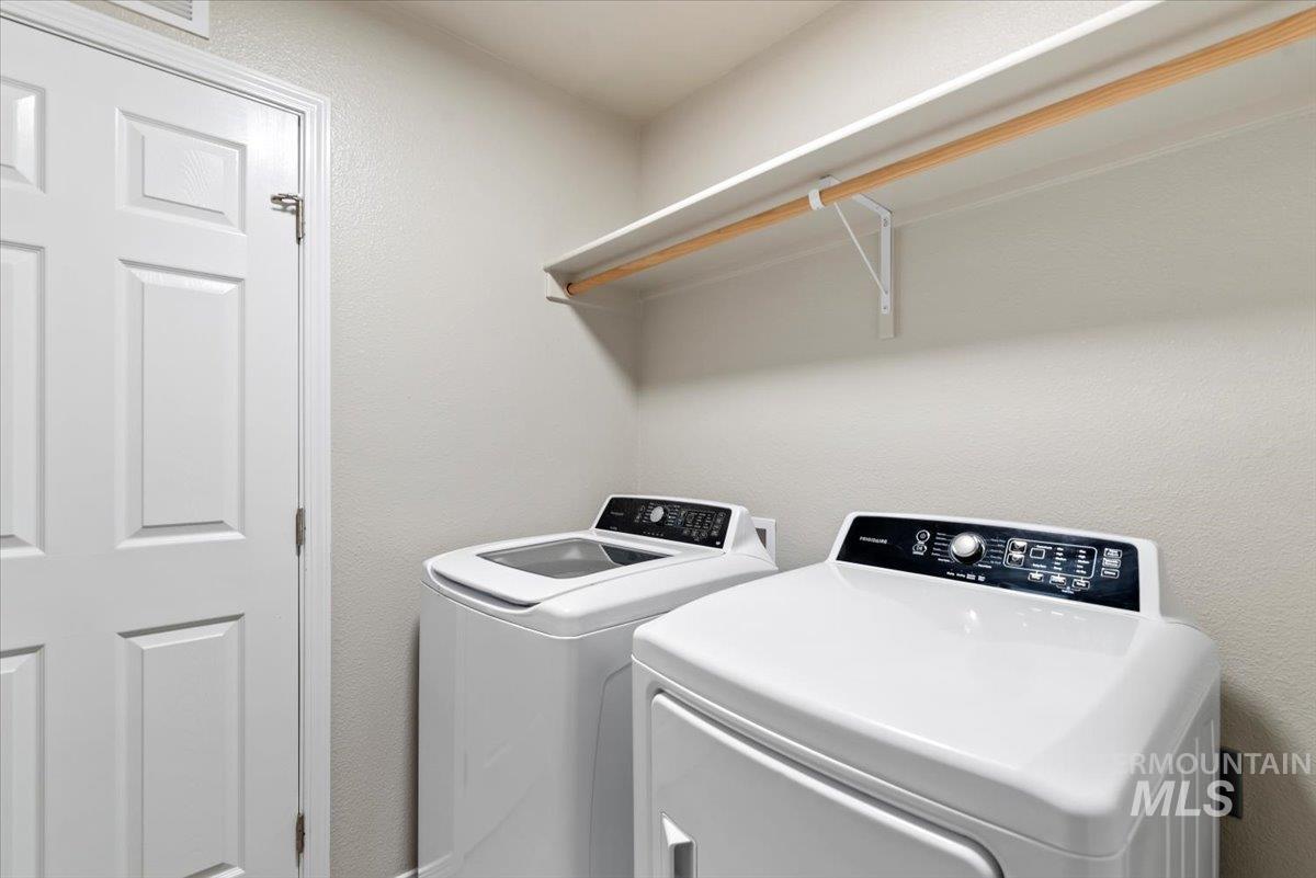 Washroom featuring a textured wall and washing machine and dryer
